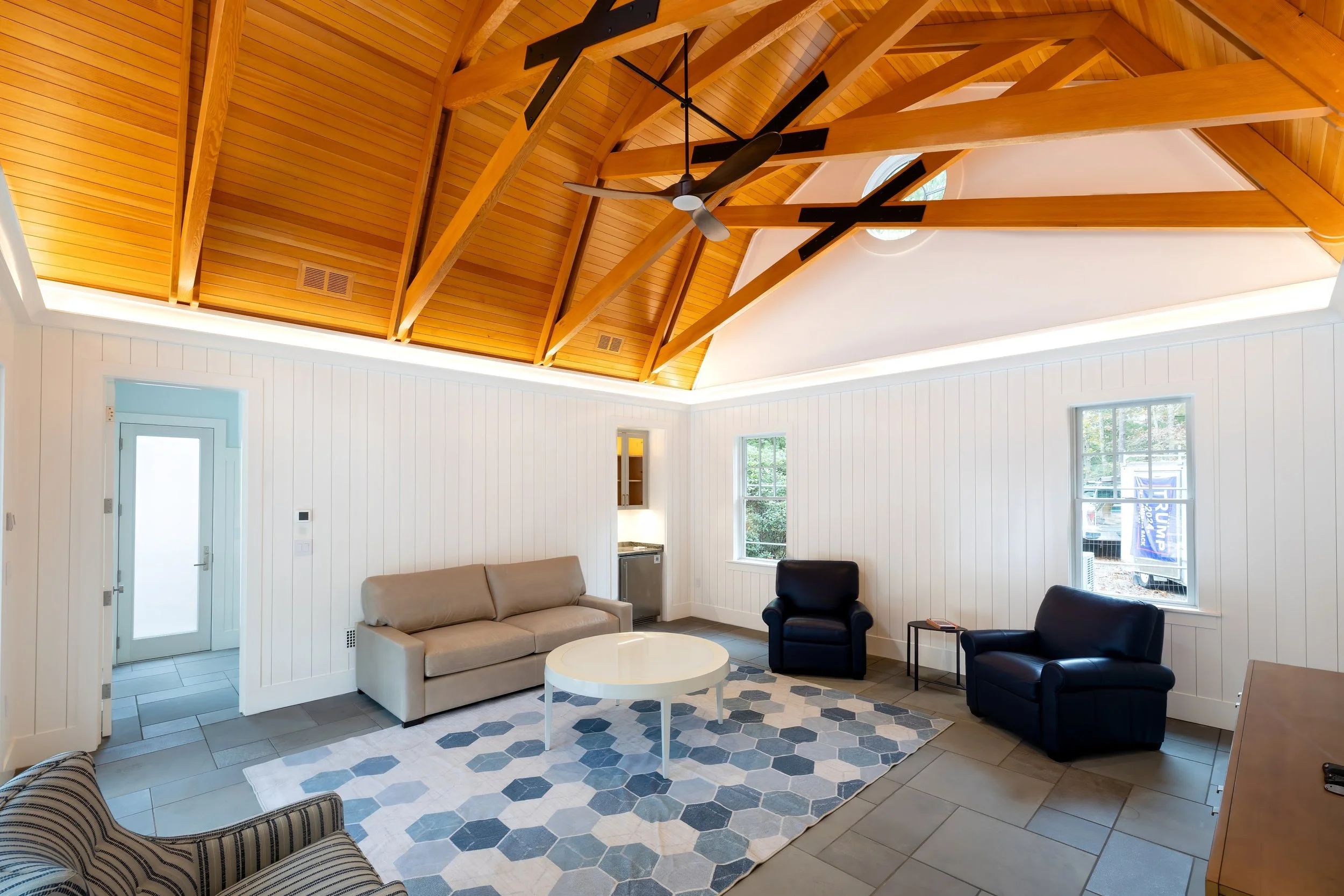 Soaring wood ceiling and white paneled walls define this Cape Cod pool house lounge.