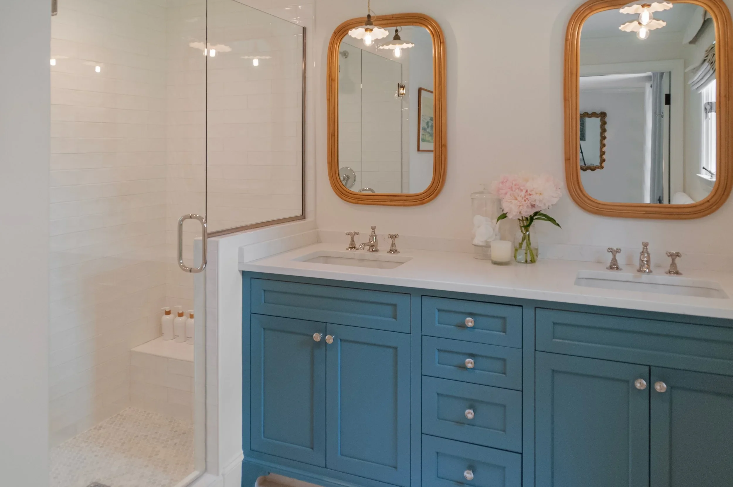 Sea View Builders designed this custom bathroom with a blue double vanity, frameless glass shower, quartz countertops, and timeless Cape Cod coastal style.