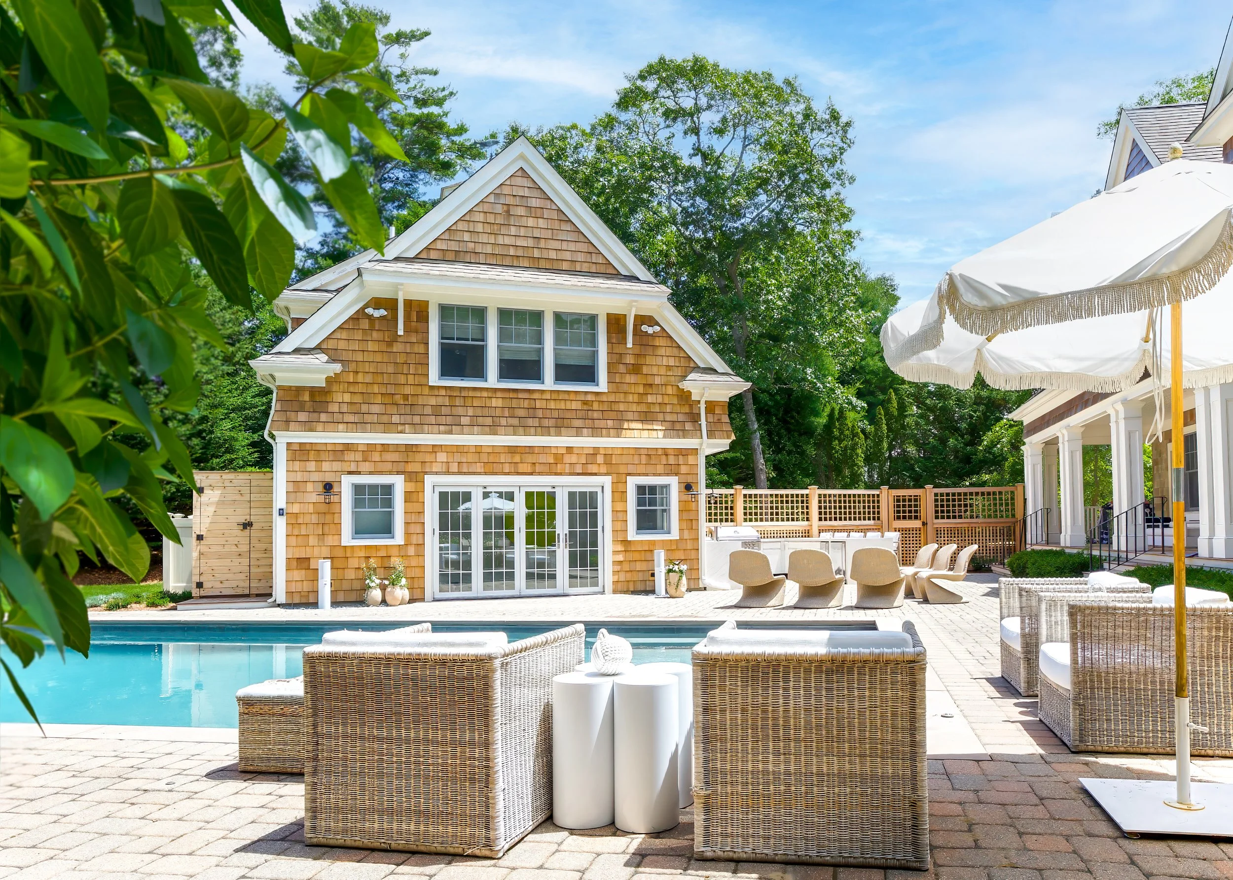 Poolside lounge area with shingled guest house, patio seating, and Cape Cod outdoor living details.