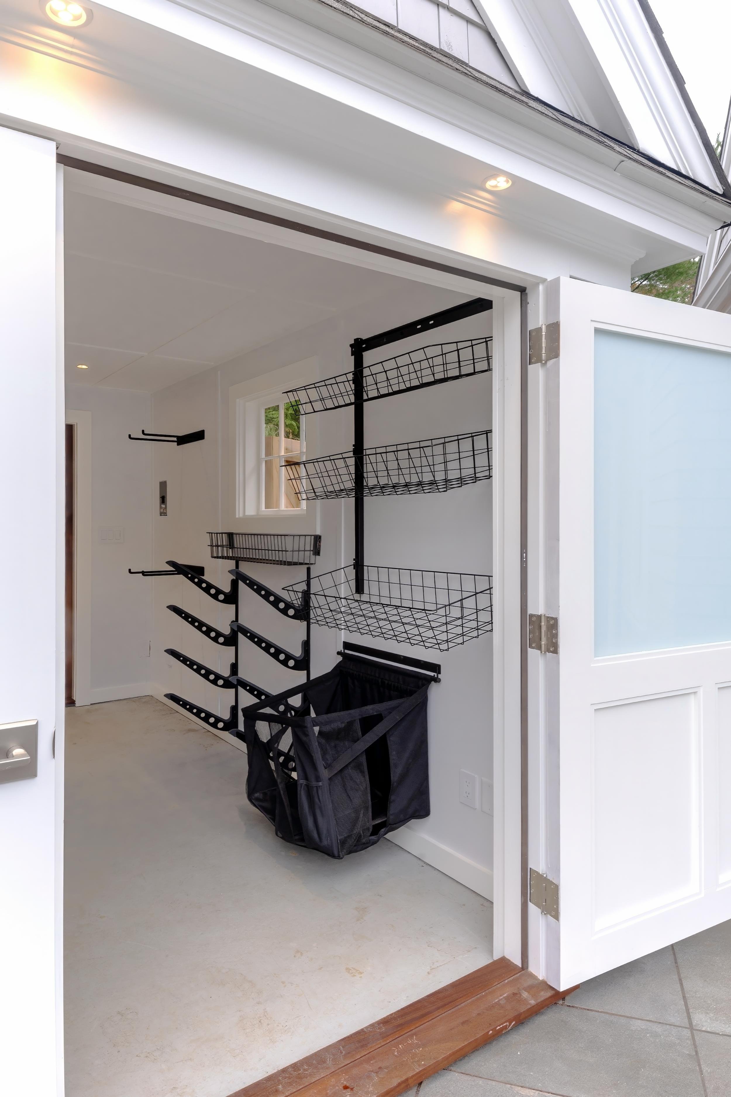 Storage room with open doors, wall mounted racks, and white interior finishes