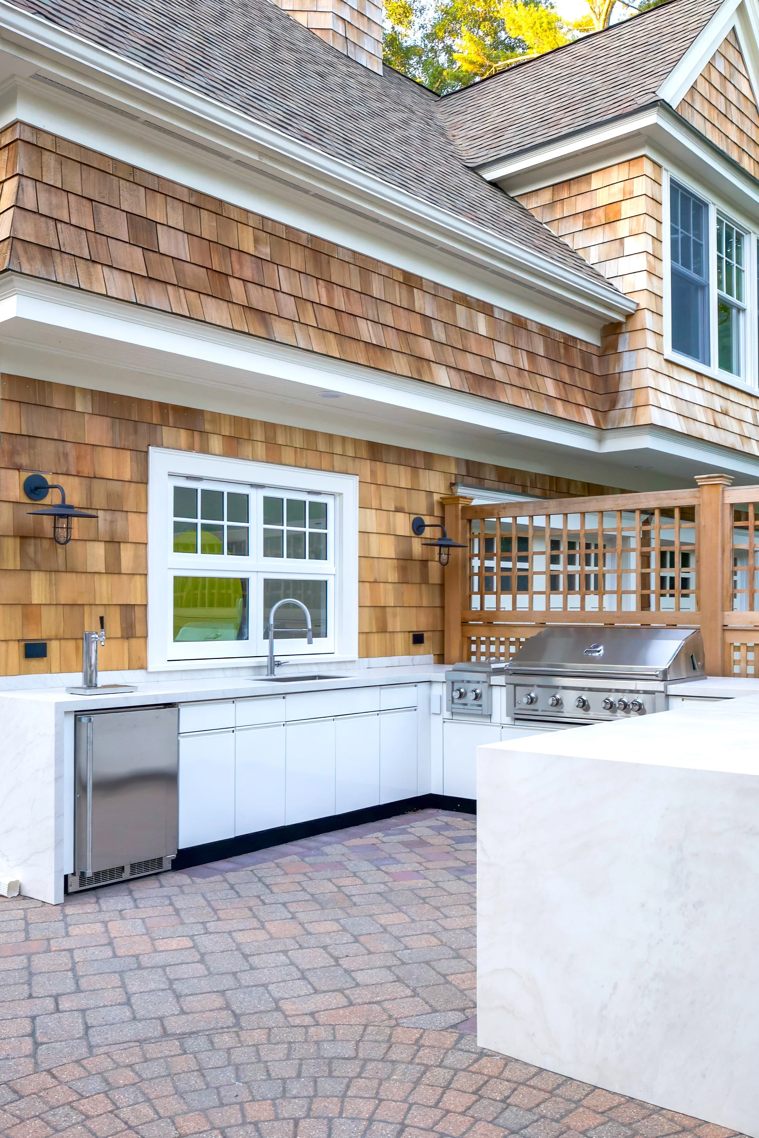 Grill station, sink, and shingled exterior create a refined Cape Cod outdoor kitchen.