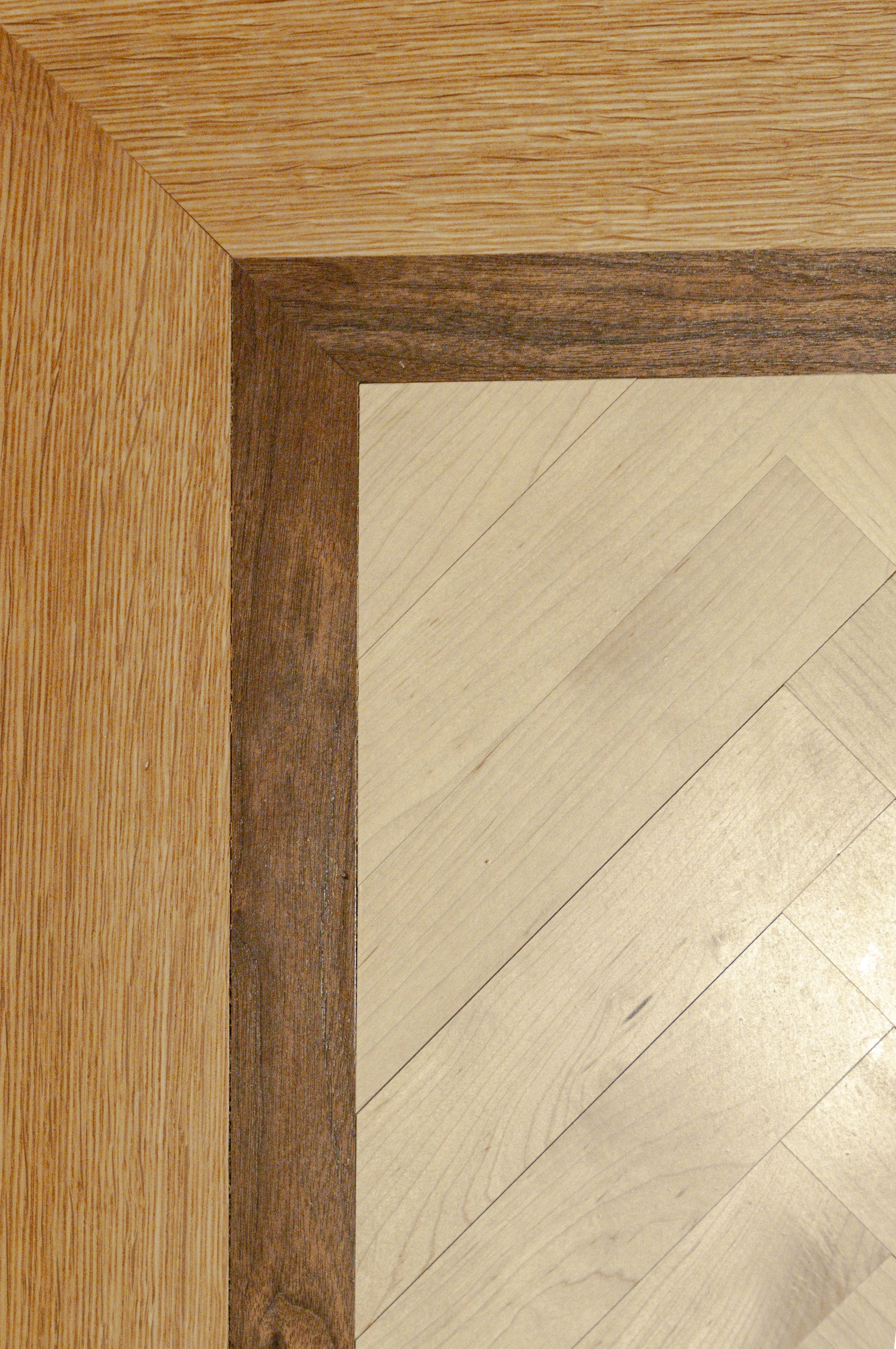 Cape Cod flooring detail with contrasting wood border, natural grain, and herringbone-patterned inset.