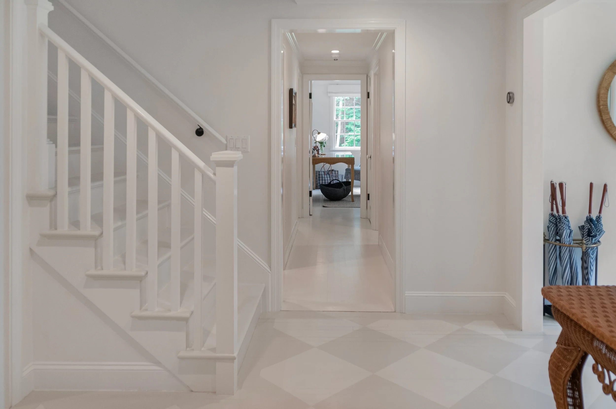 Checkered flooring and white staircase add classic detail to this Cape Cod entryway design.