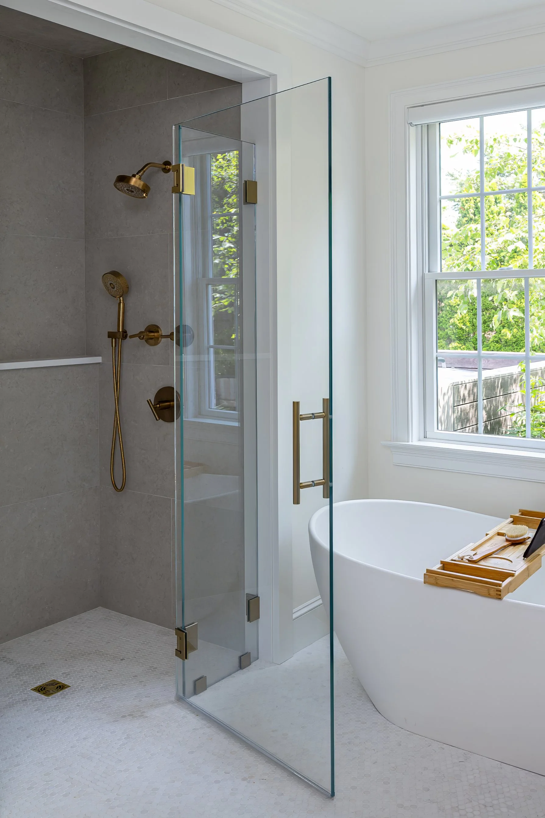 Frameless glass shower, freestanding soaking tub, and oversized windows create a bright, spa-inspired primary bathroom.