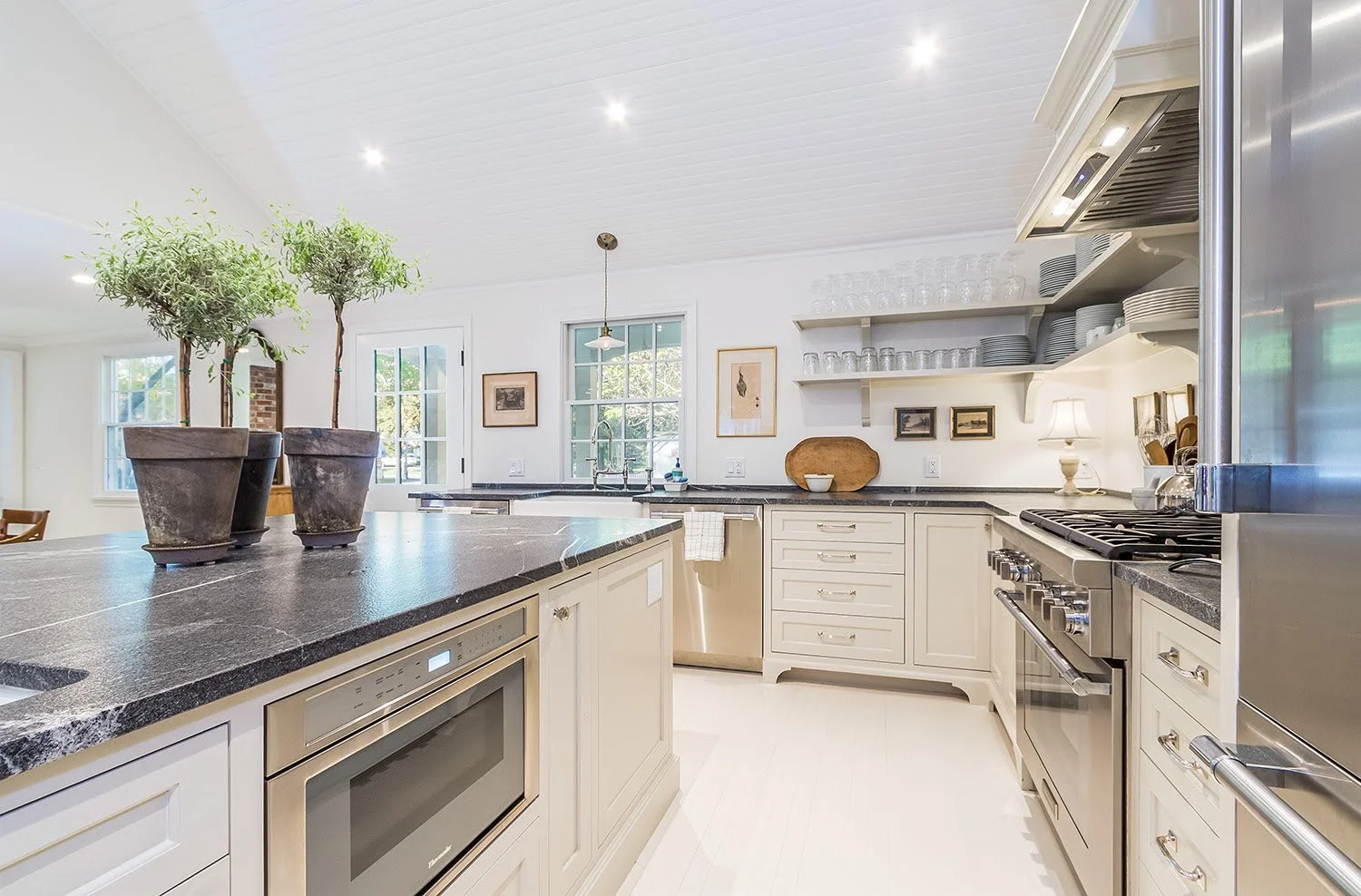 Luxury Cape Cod kitchen in a custom coastal home with stone counters, paneled ceilings, and professional stainless appliances.