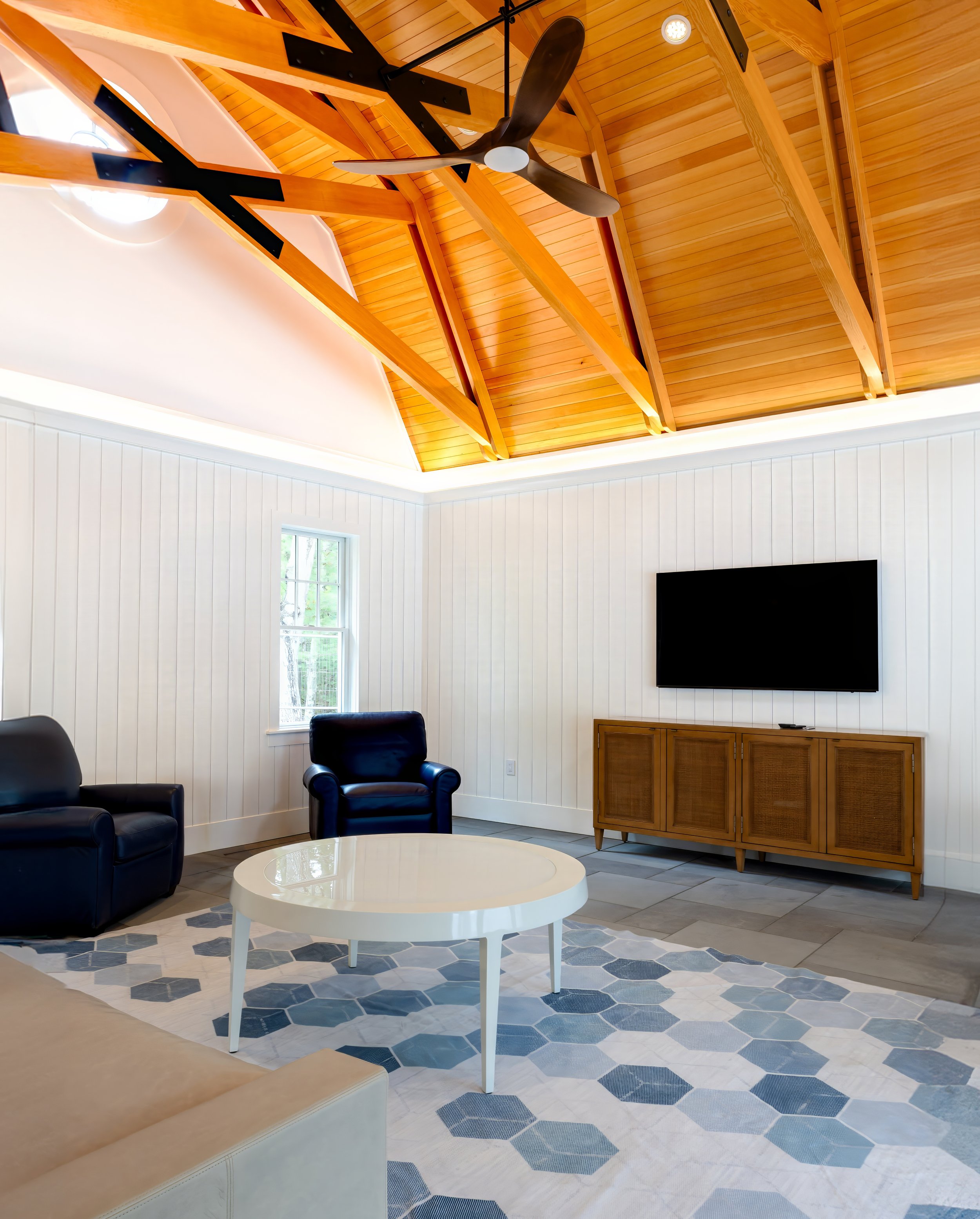 Pool house living room with vaulted wood ceiling, exposed beams, and coastal furnishings.