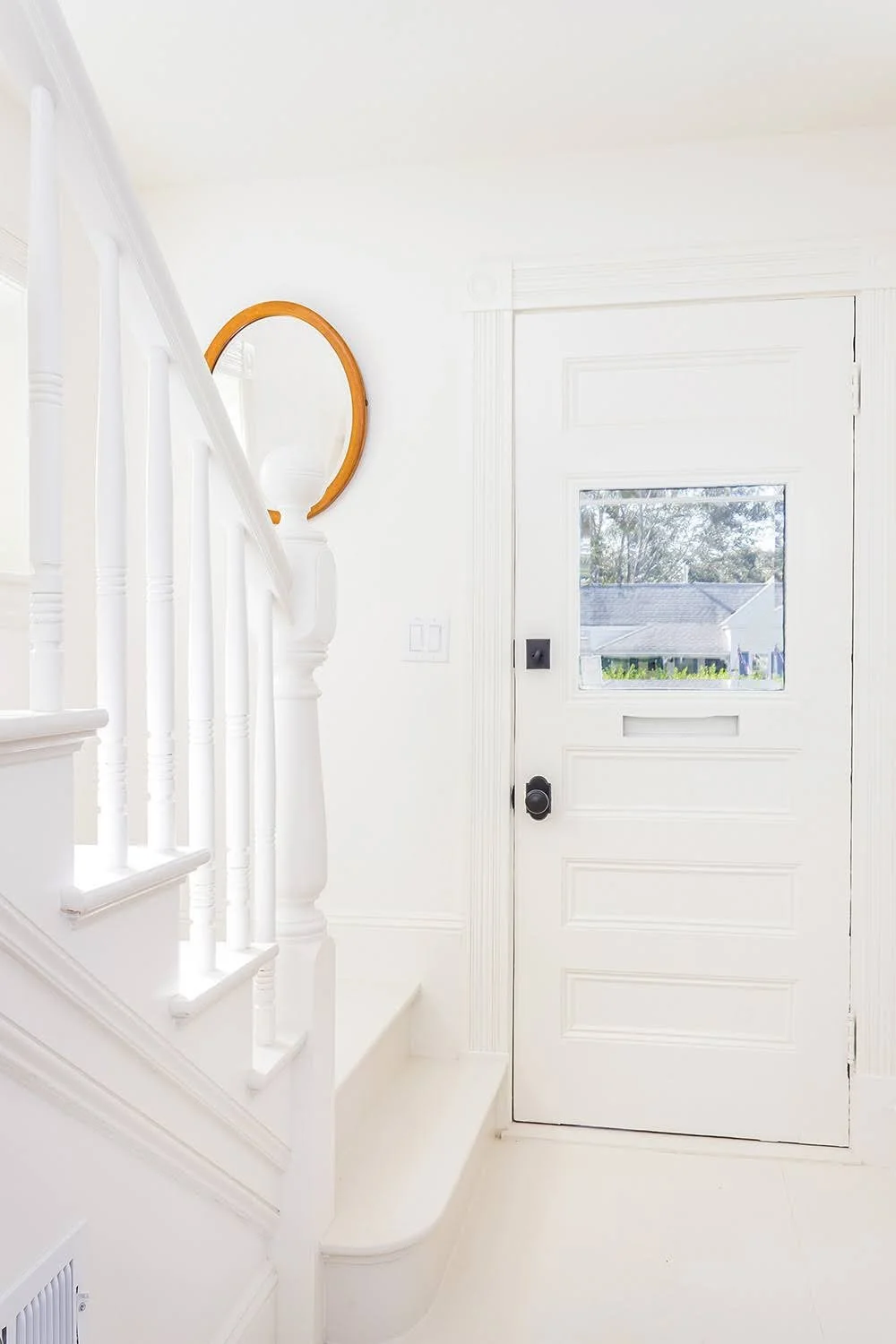Bright stair landing with white railing, lantern pendant, and classic Cape Cod cottage renovation details.