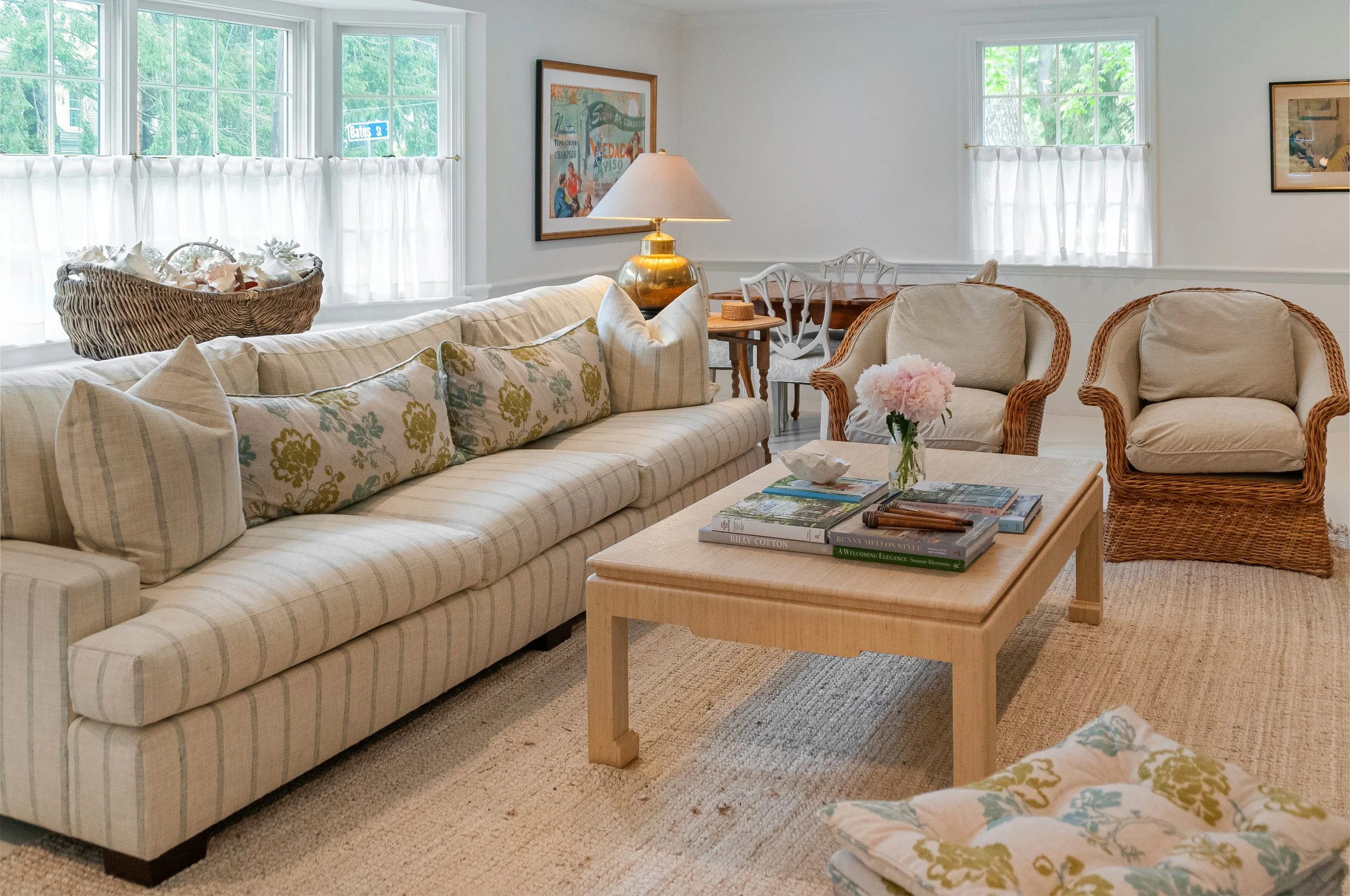 Striped sofa and wicker chairs create relaxed coastal living room design with soft window light.