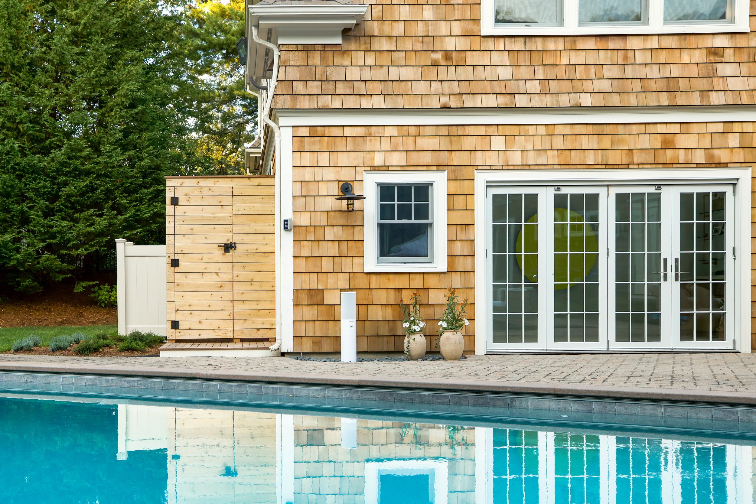 French doors, pool , and cedar shingles highlight this homes poolside exterior.
