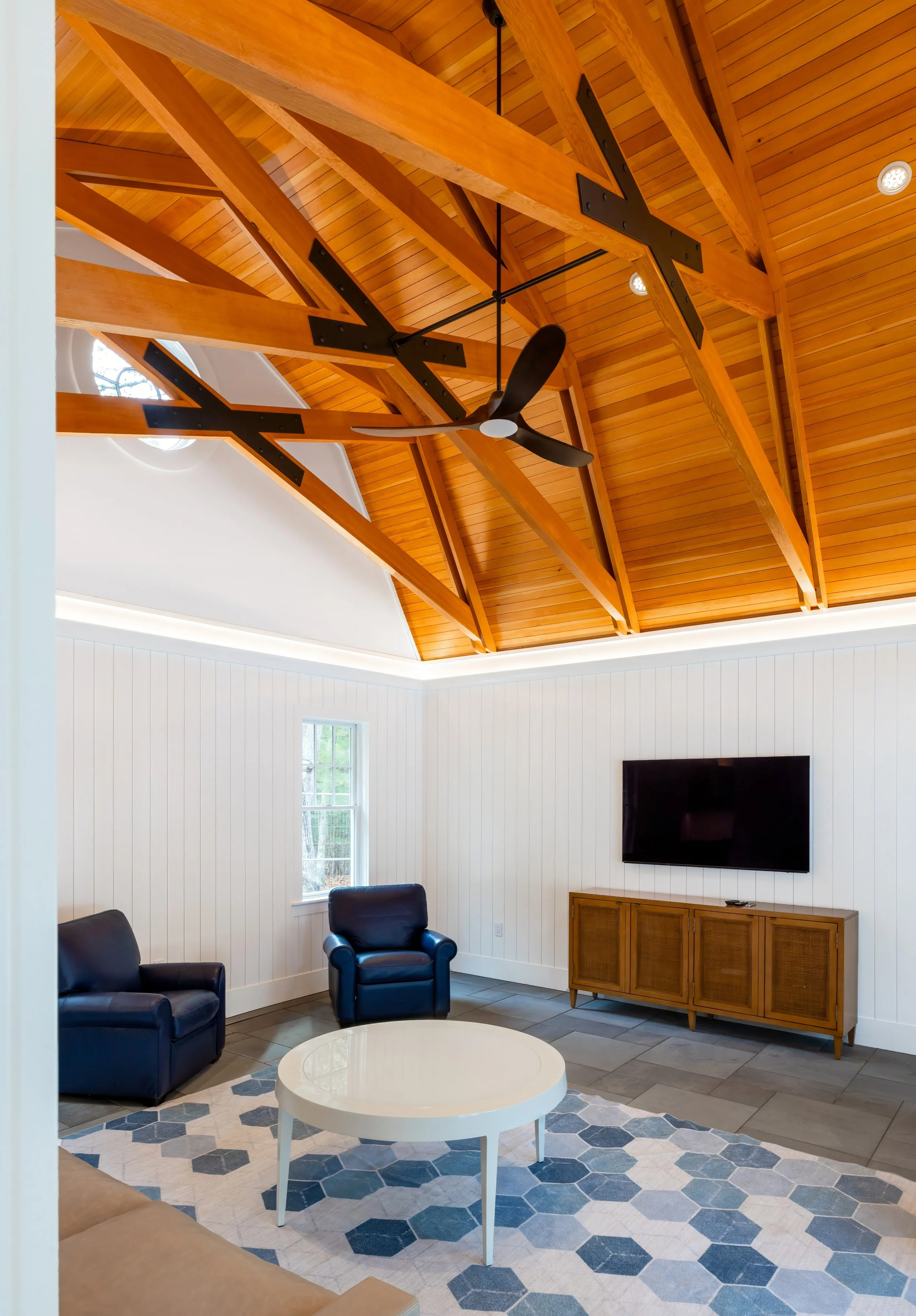 Exposed wood trusses, tongue-and-groove cedar ceilings, and a soaring vaulted design showcase the architectural detail of this custom Cape Cod home.