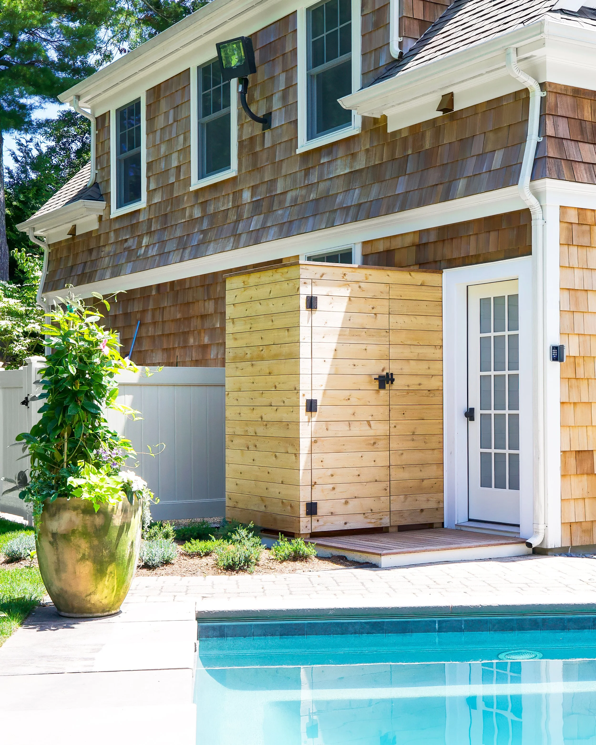 Outdoor cedar shower and shingled exterior add privacy and texture to this custom coastal home on Cape Cod.