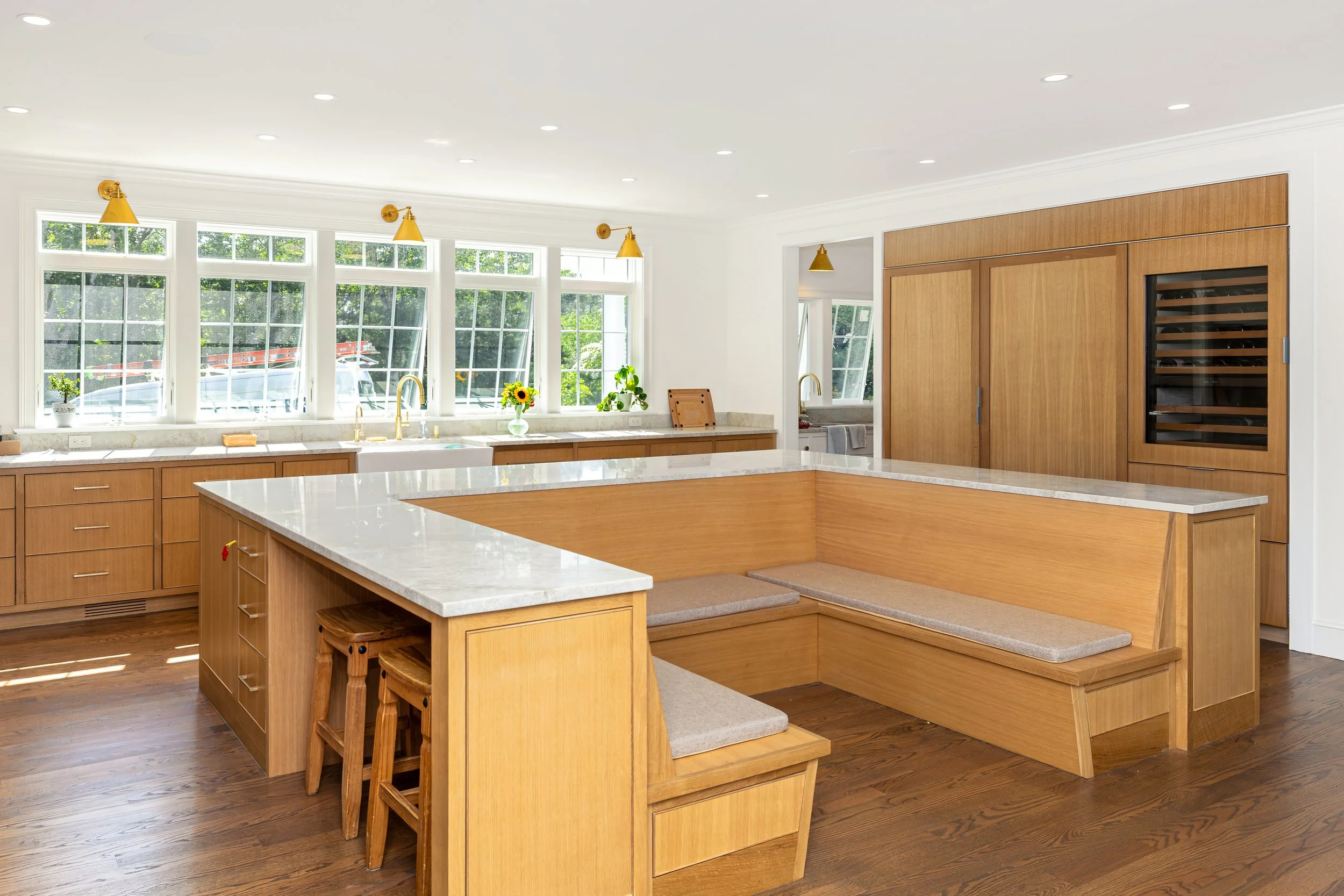 Designed for gathering, this custom kitchen combines a large quartz island, integrated breakfast nook, white oak cabinetry, and spacious open-concept living.