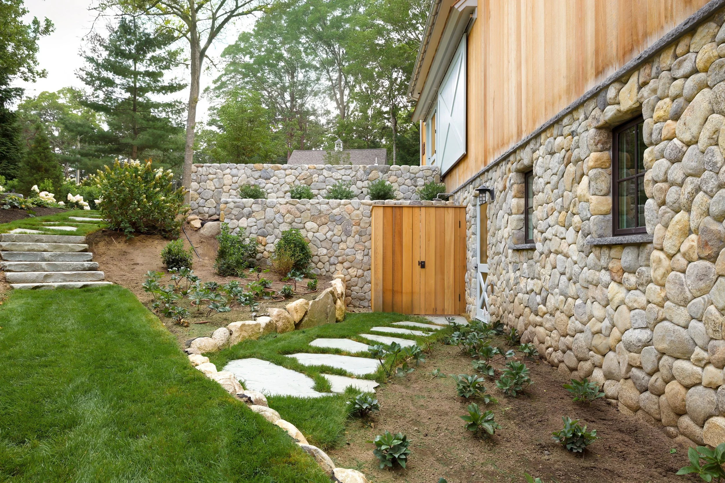 Stone Foudation, garden steps, wood doors, and layered landscaping 