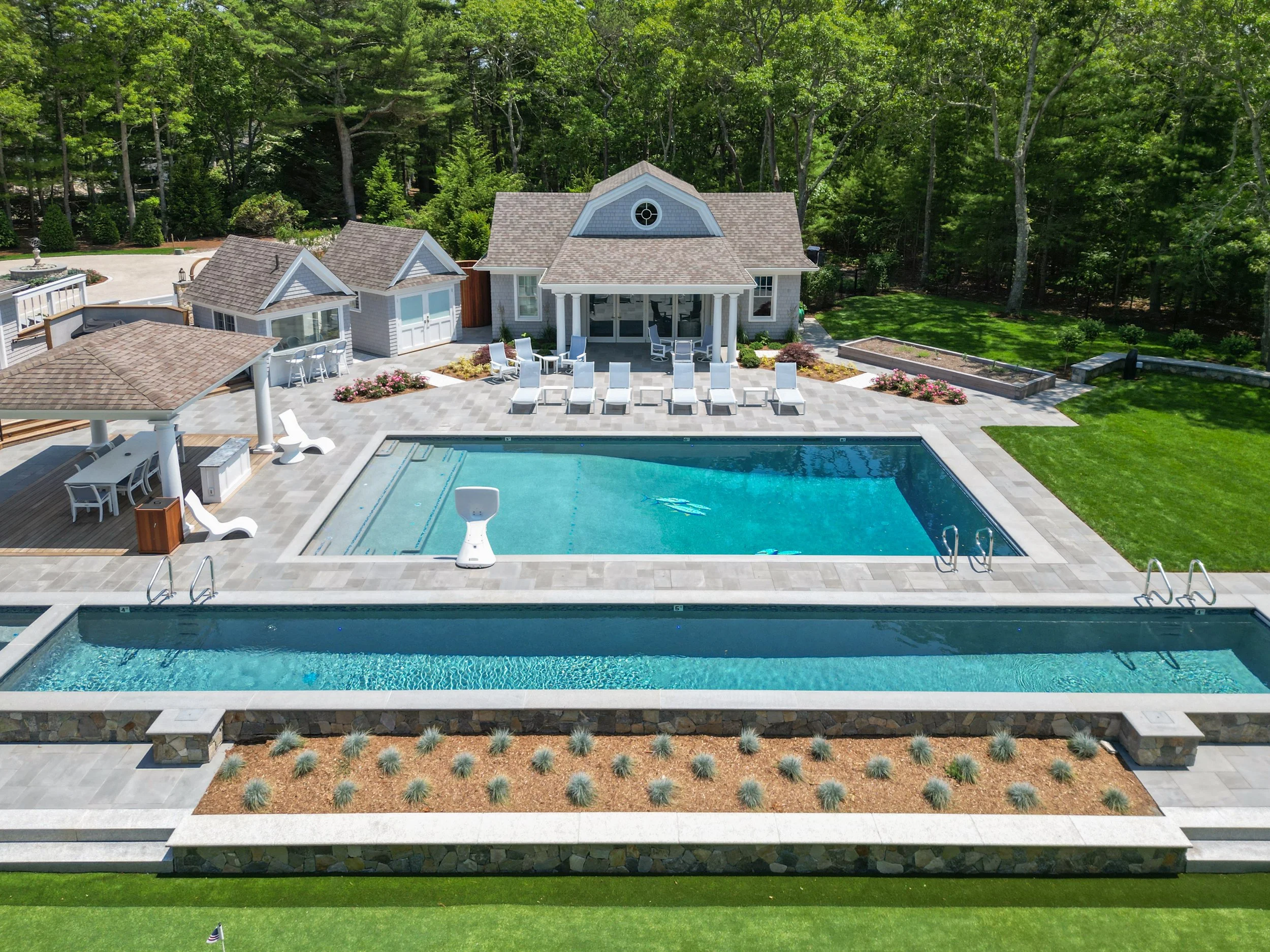 Expansive pool terrace with cabana, lounge seating, and manicured landscaping at a custom coastal home.