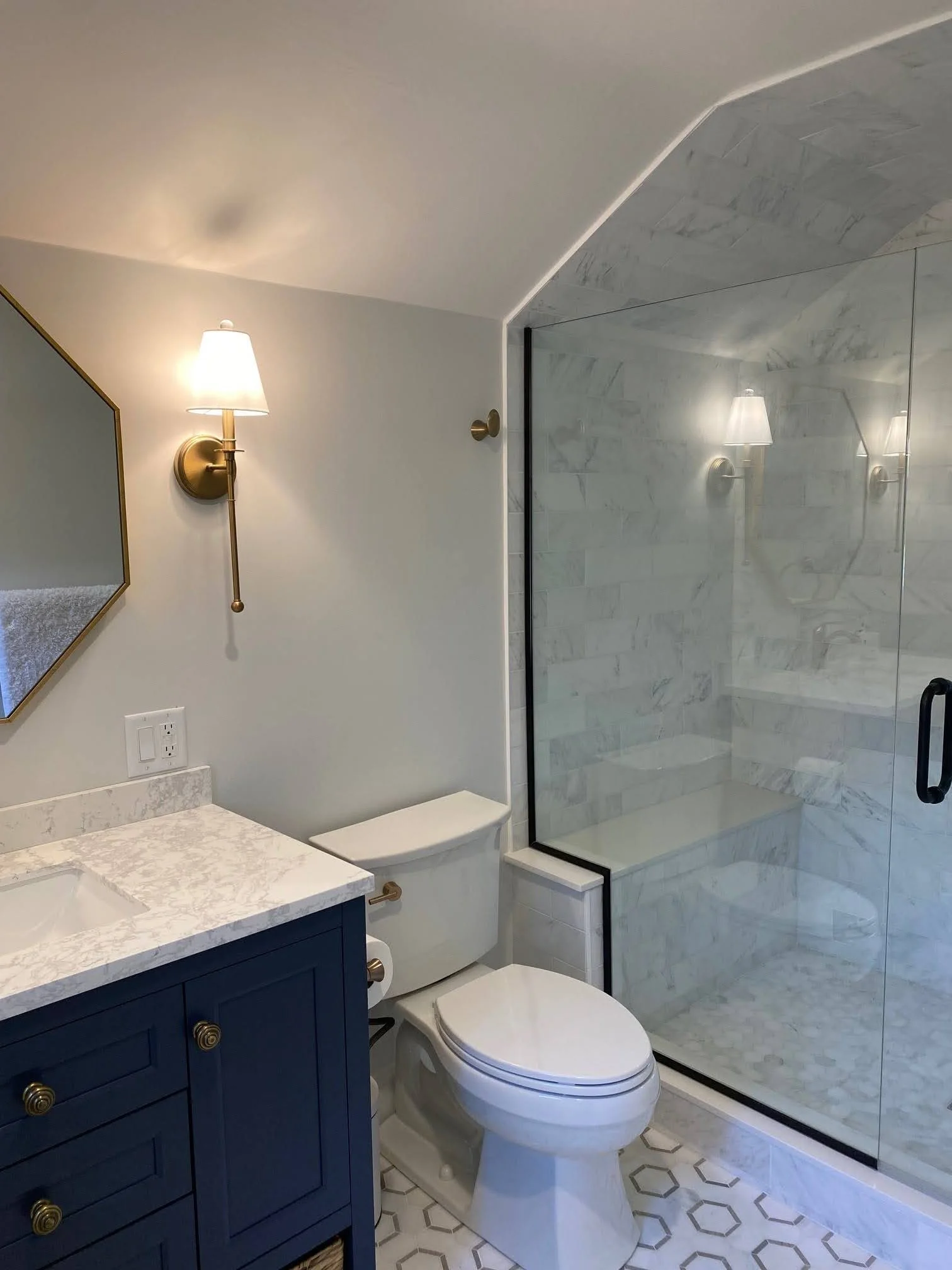 A marble glass shower and navy vanity bring high-end Cape Cod renovation detail to this compact bathroom.