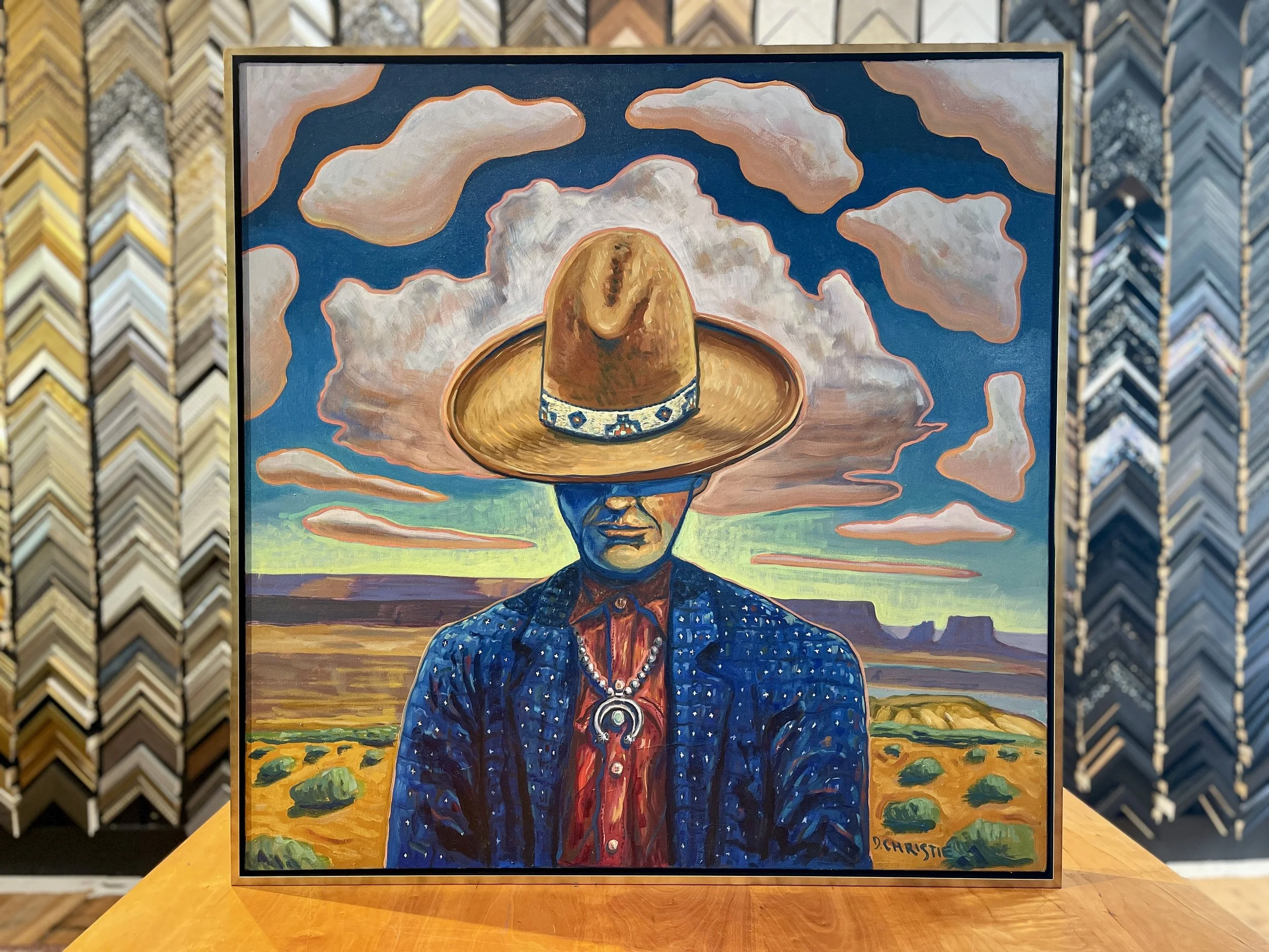 A painting of a person with a cowboy hat covering their eyes, set against a desert landscape with clouds in the sky.