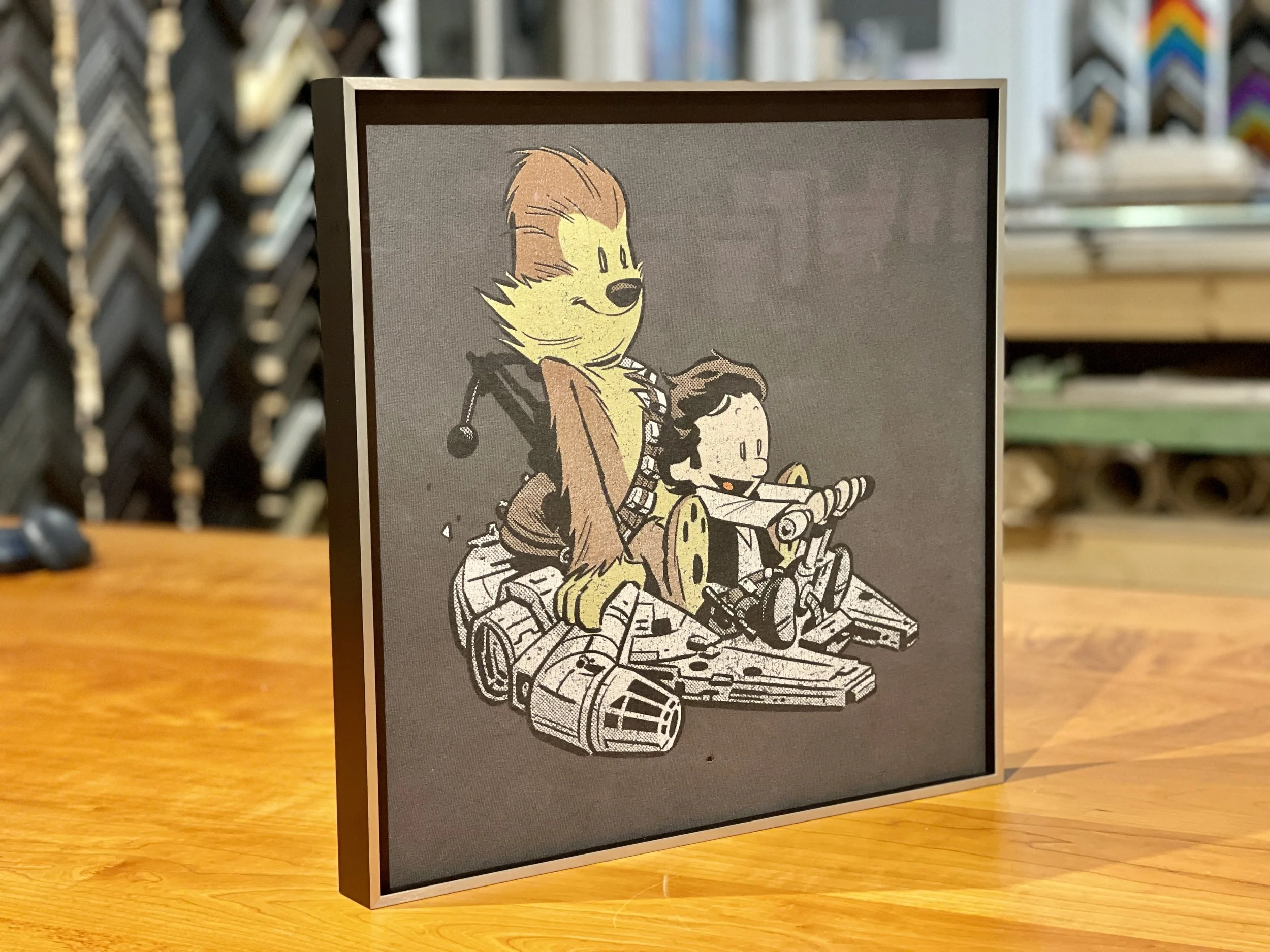 A framed cartoon print of Rocket Raccoon and baby Groot from Guardians of the Galaxy riding in a spaceship.