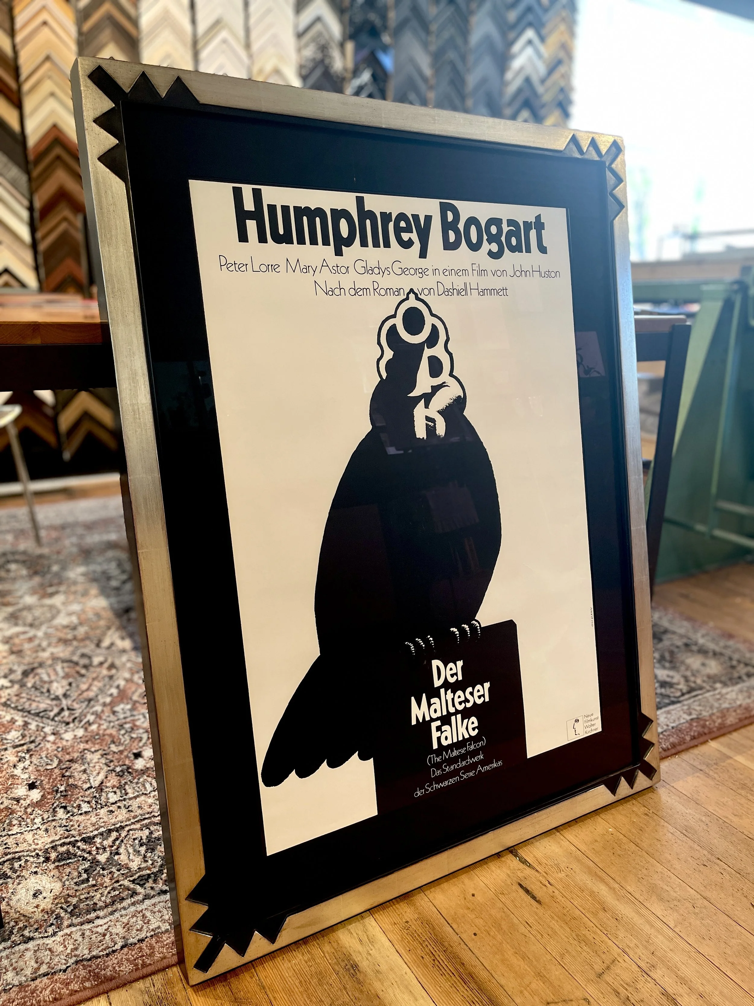 Poster advertising the film "Der Malteser Falke" featuring a black silhouette of a falcon on top of a Maltese cross, with text in German and English.