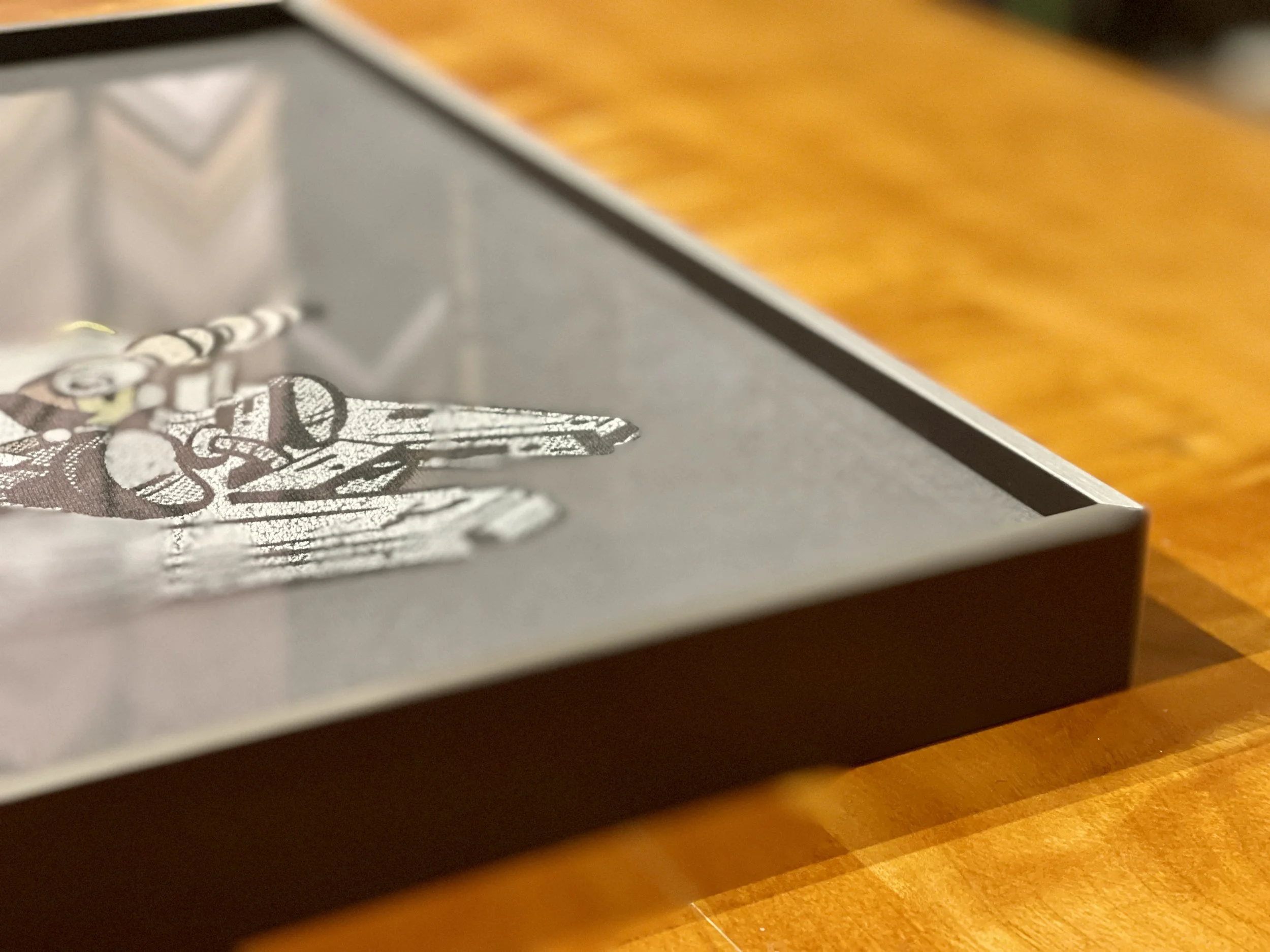 Close-up of a gray box with a cartoon character illustration on the lid, placed on a wooden surface.
