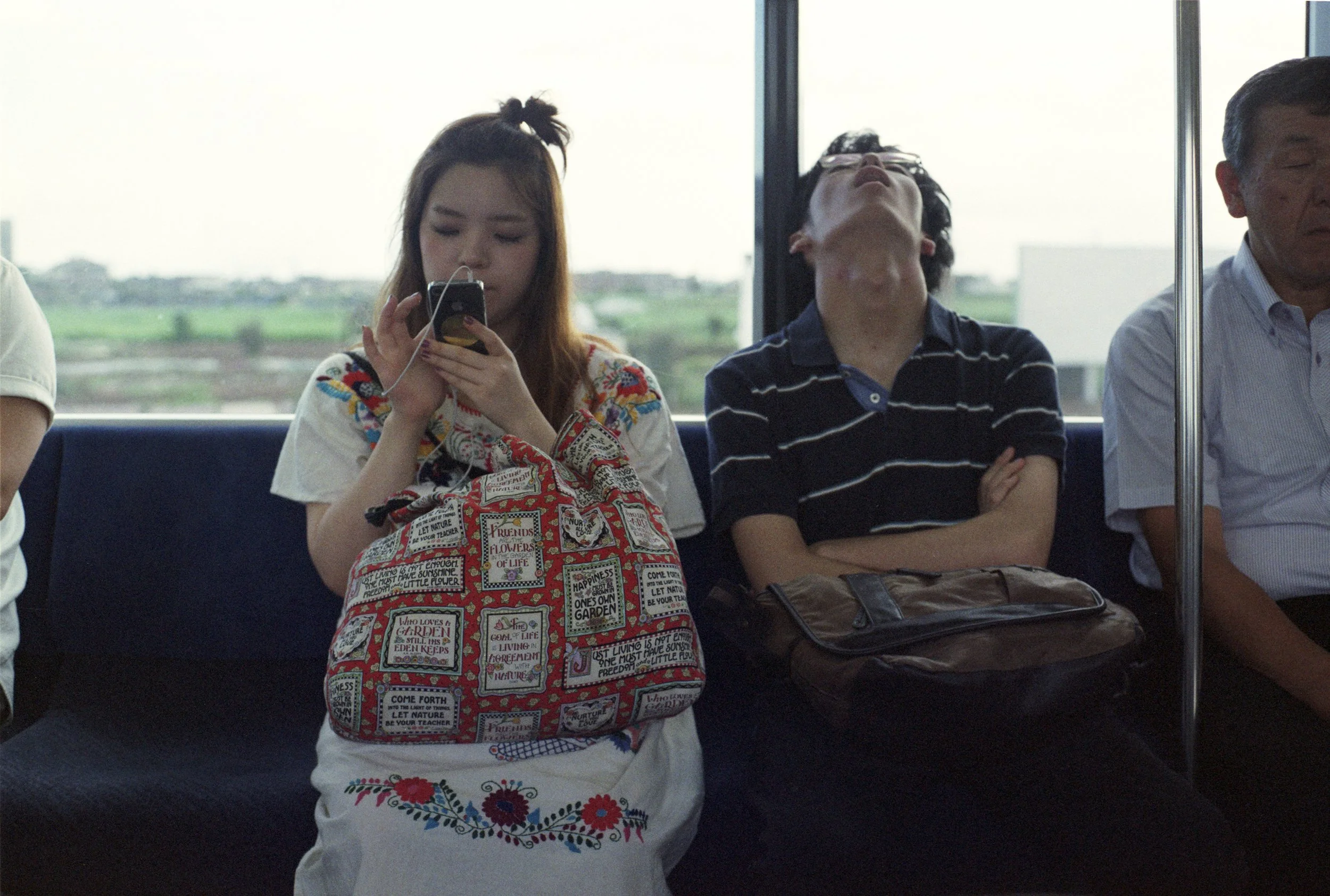 girl on phone sitting beside boy sleeping hard on train * ennis 35mm film photography japan street 2012
