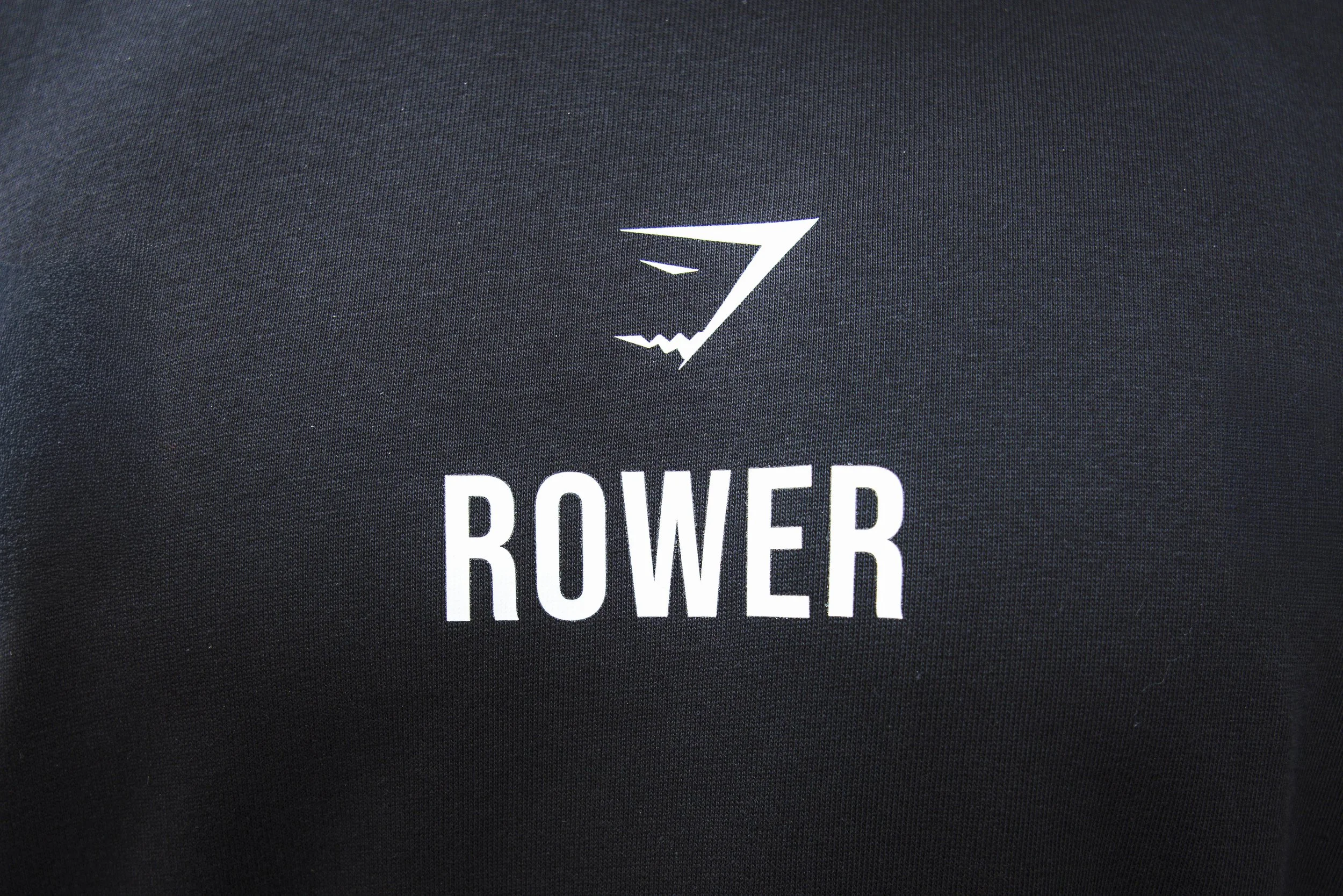 A black fabric surface with a white logo of a stylized sailboat and the word 'ROWER' printed below it.