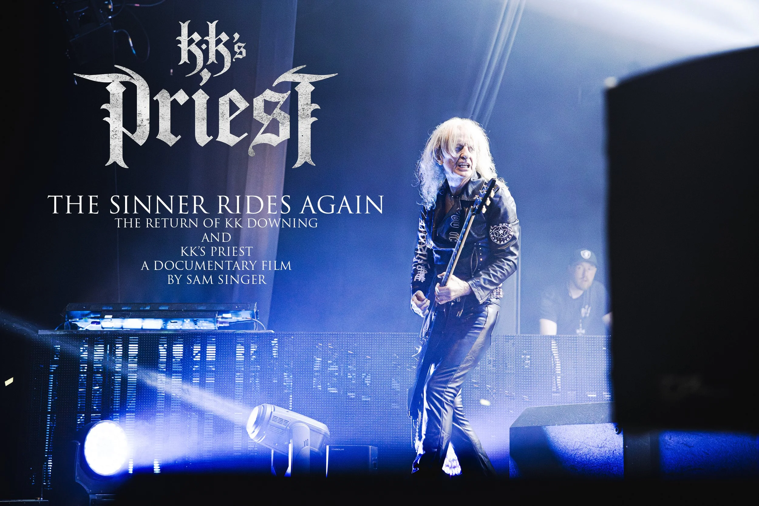 Concert scene showing a guitarist with long blond hair wearing a black leather jacket with patches, playing on stage illuminated by blue and white lights. A large screen behind displays the text 'KK's Priest: The Sinner Rides Again,' with additional information about a documentary by Sam Singer.