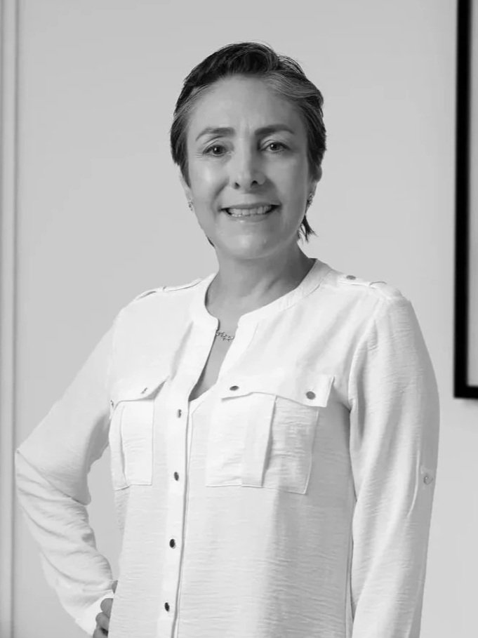 Retrato en blanco y negro de una mujer sonriendo, con cabello corto y blusa de seda, usando un collar y aretes.