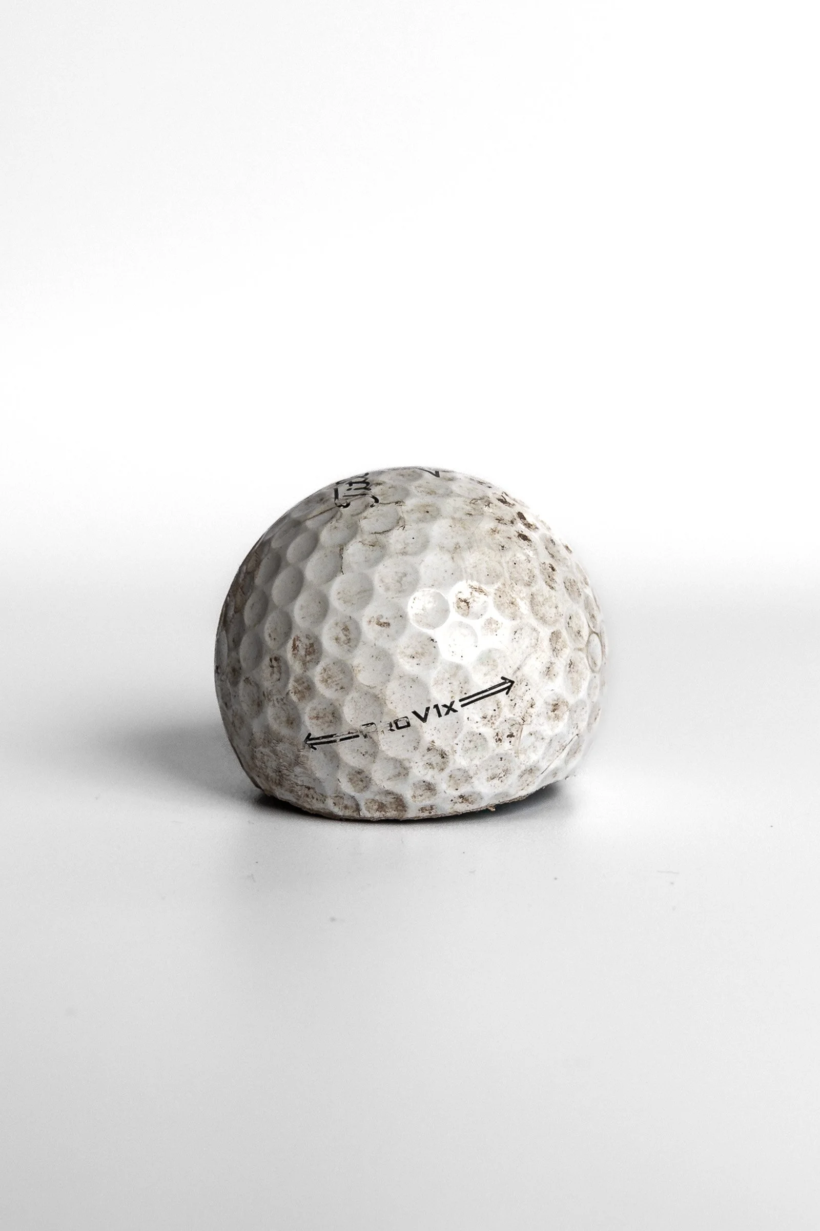 Titleist Pro V1x aged golf ball with dirt and wear marks white background