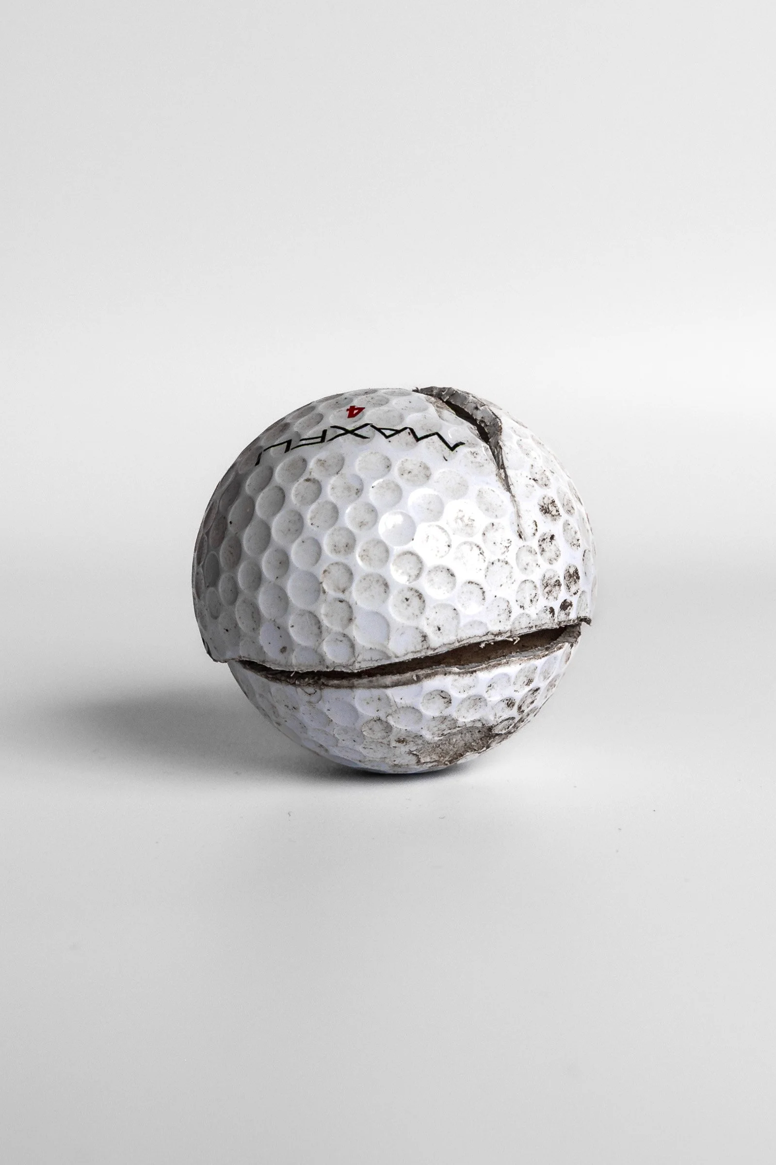 Maxfli Revolution golf ball split along equator showing dark interior white background