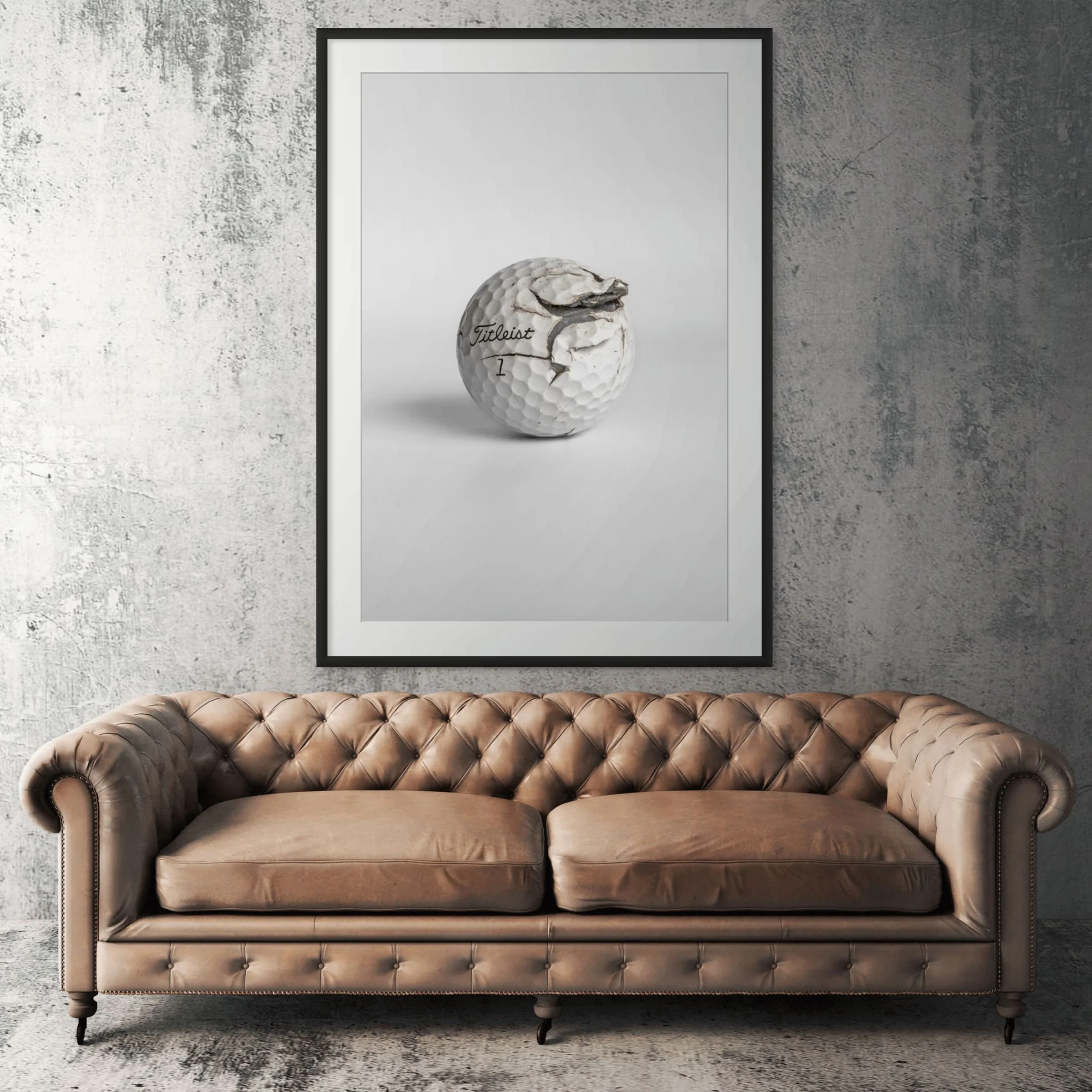 Titleist Pro V1 fractured golf ball framed print displayed above tan leather sofa in living room