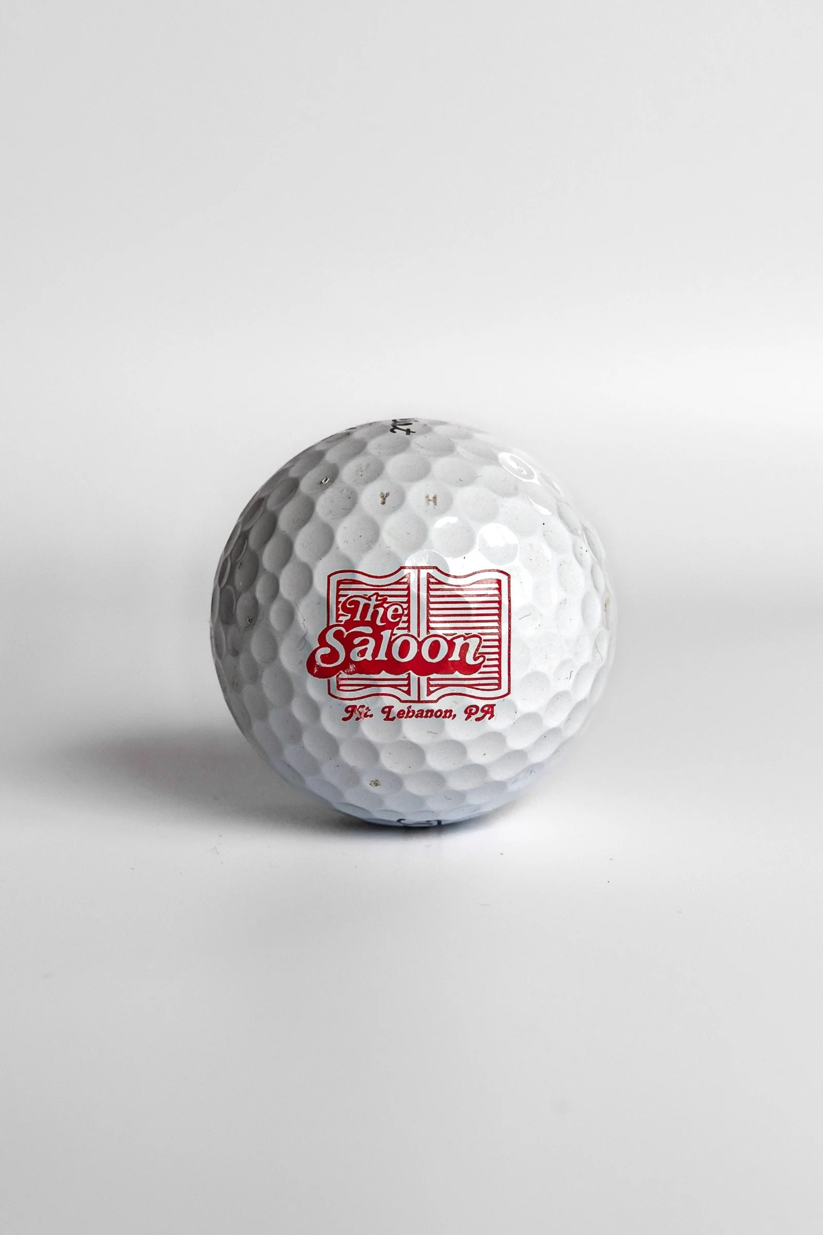 Titleist Pro V1 golf ball with The Saloon Mt. Lebanon PA red logo white background
