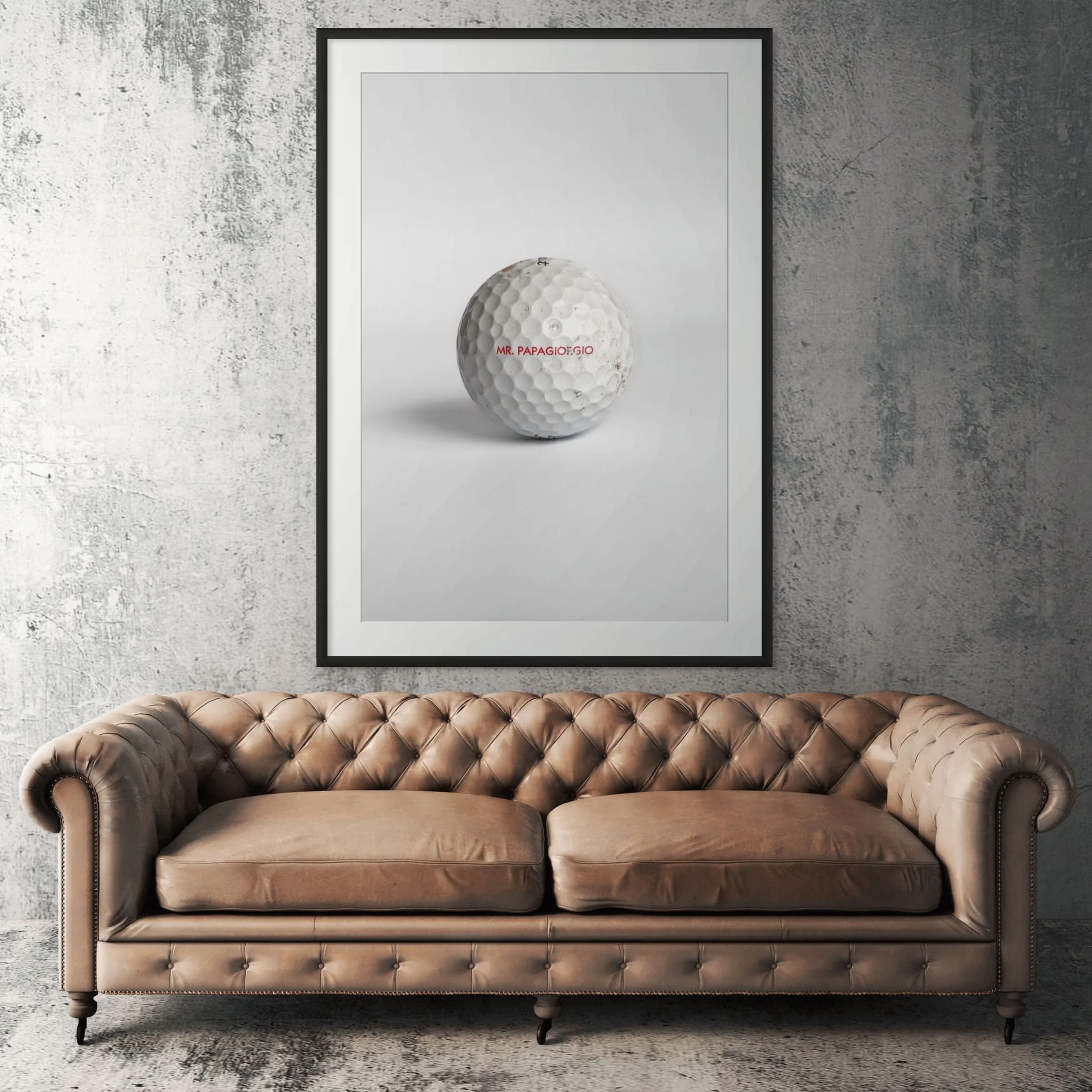 Titleist Pro V1x Mr. Papagiorgio golf ball framed print displayed above tan leather sofa in living room
