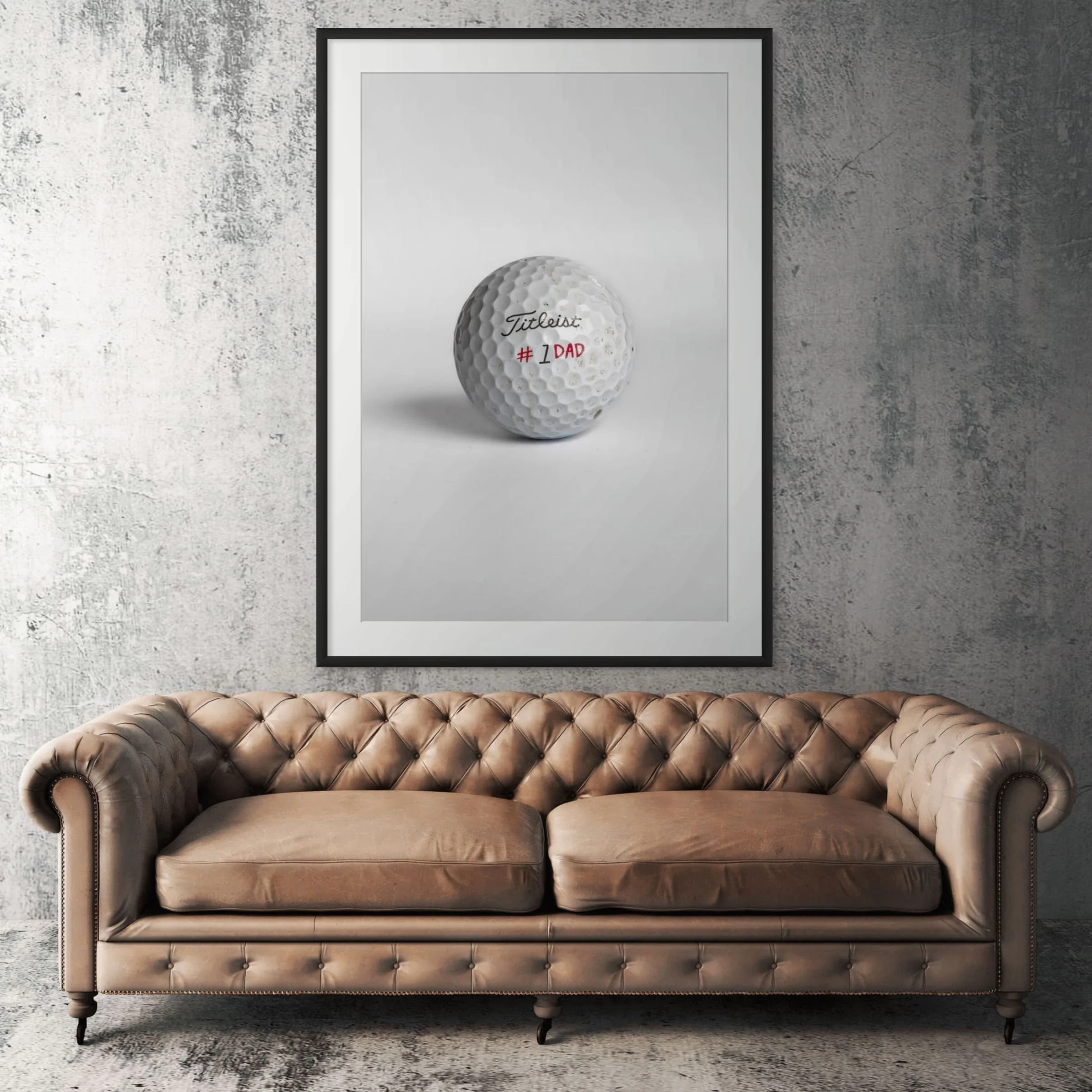 Titleist Pro V1 number one dad golf ball framed print displayed above tan leather sofa in living room