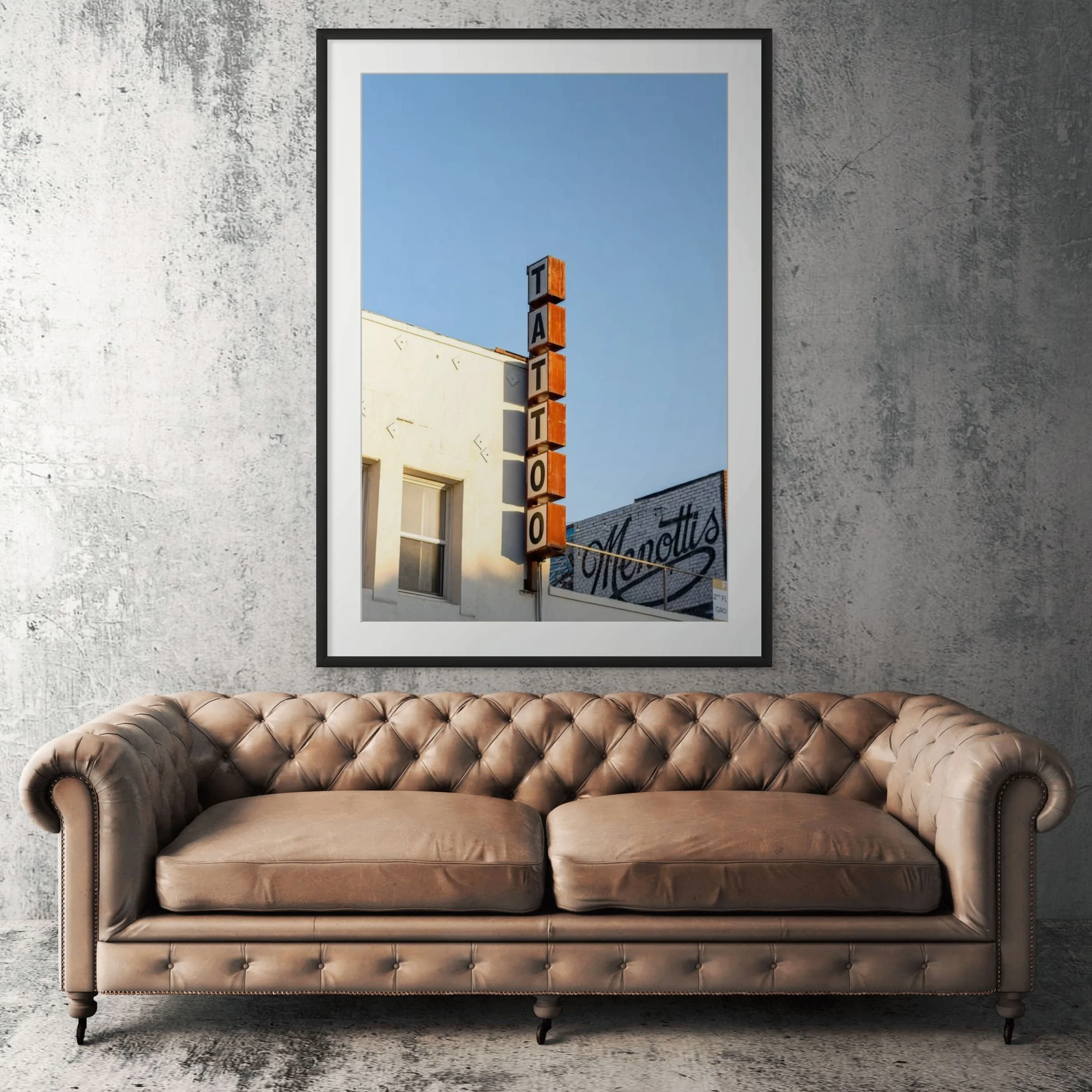 Venice Beach tattoo shop framed print displayed above tan leather sofa in living room