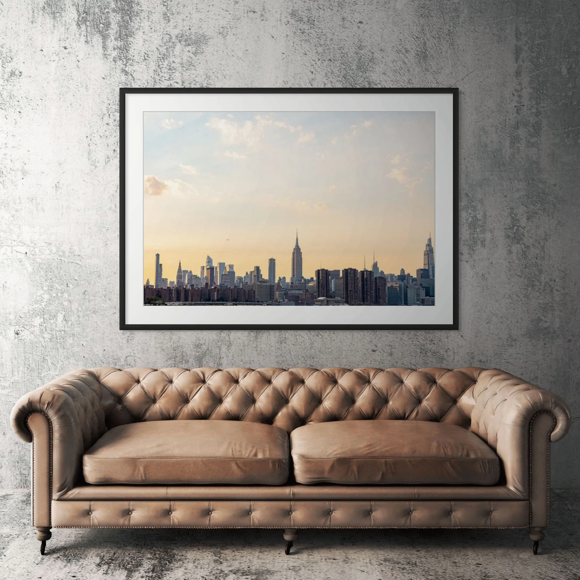 Manhattan skyline framed print displayed above tan leather sofa in modern living room