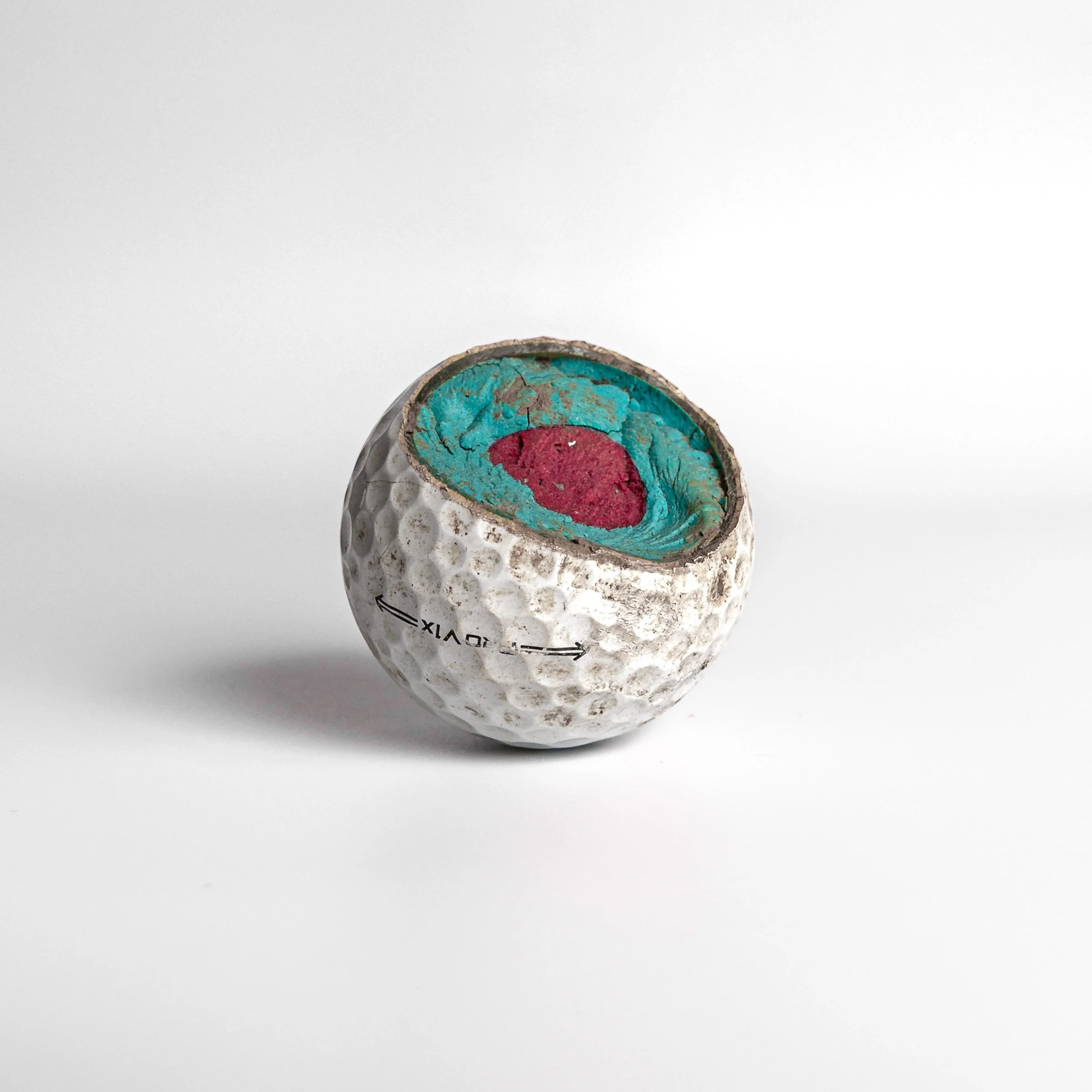 Titleist Pro V1 cut open showing turquoise and pink interior core layers white background