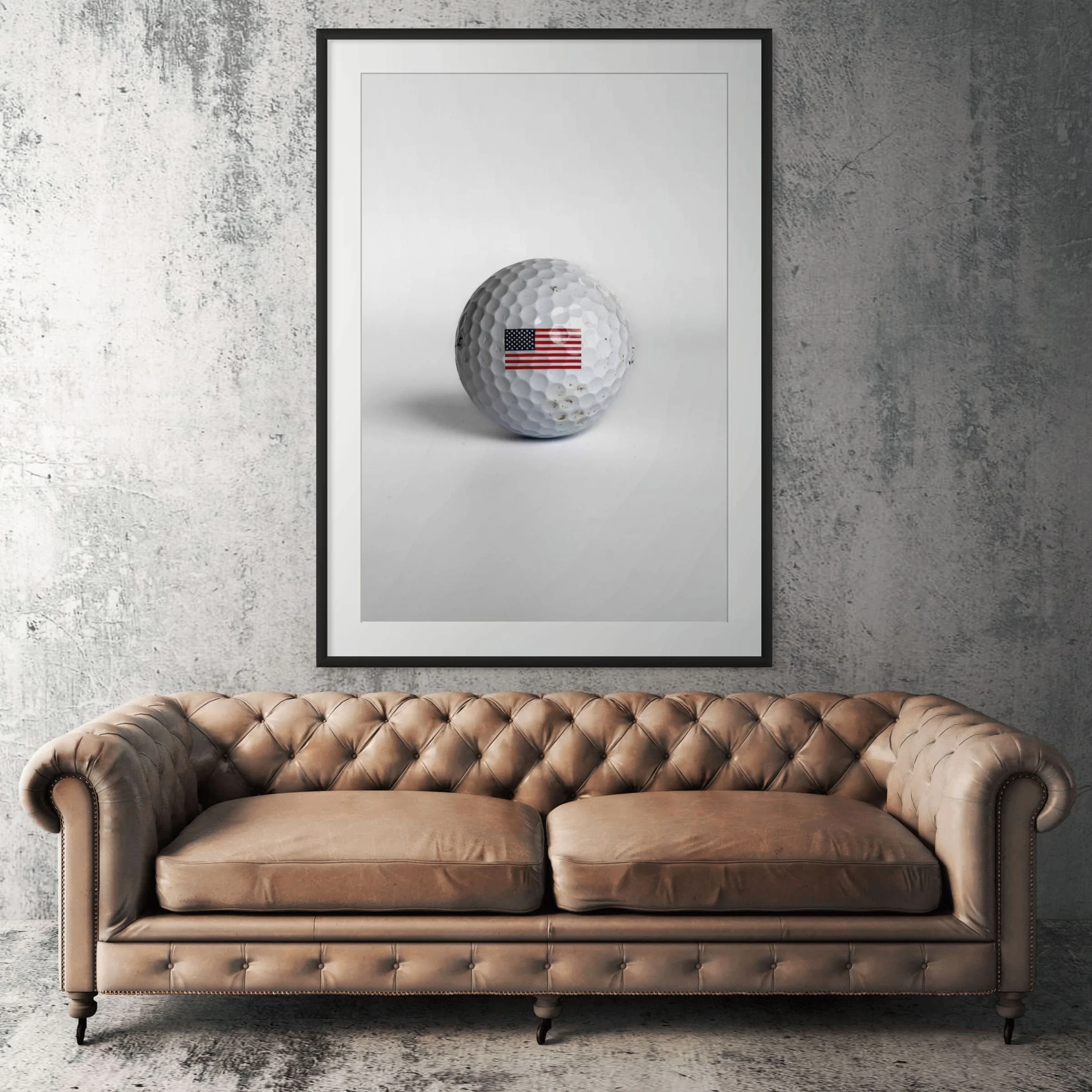 Titleist Pro V1 American flag golf ball framed print displayed above tan leather sofa in living room