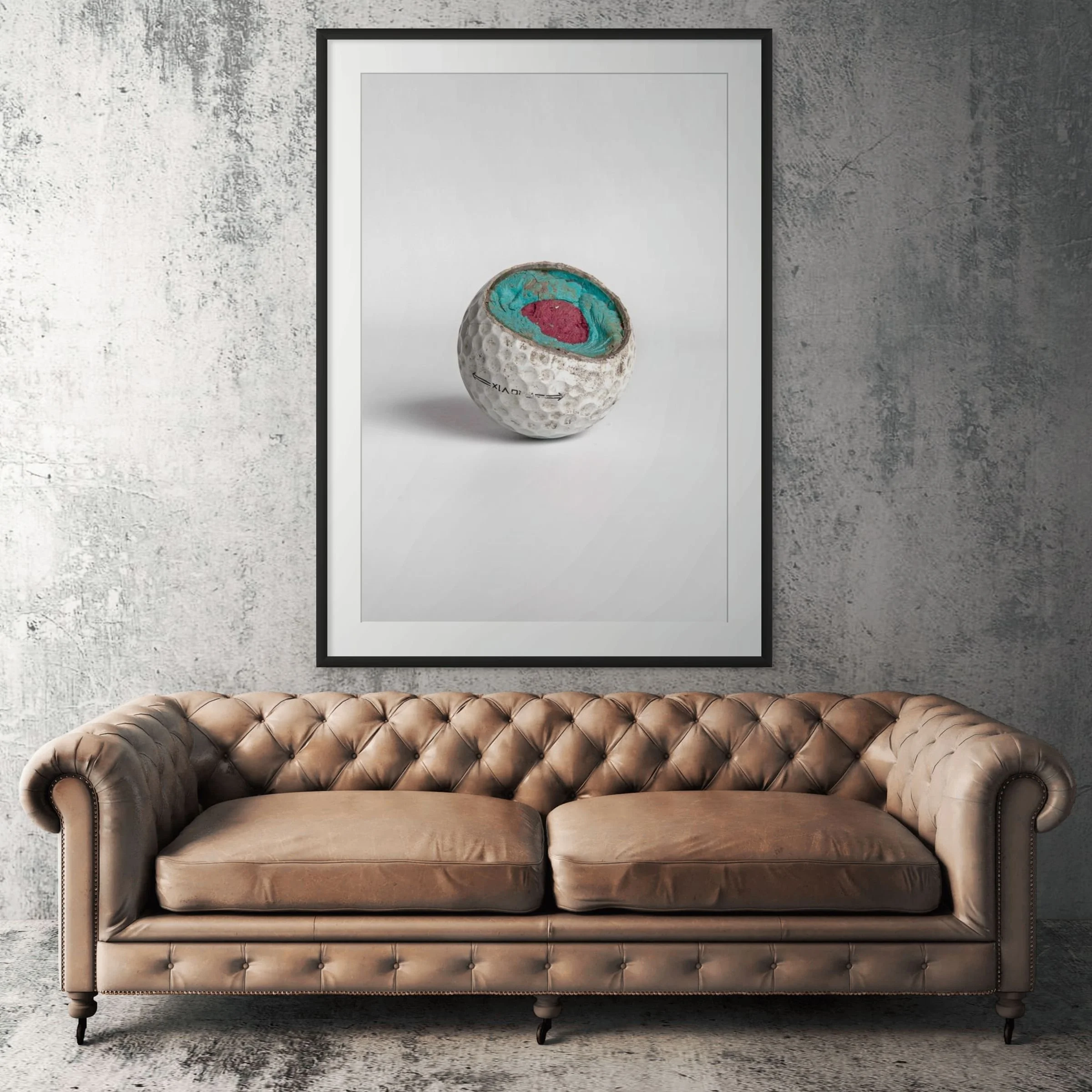 Titleist Pro V1 exposed core golf ball framed print displayed above tan leather sofa in living room