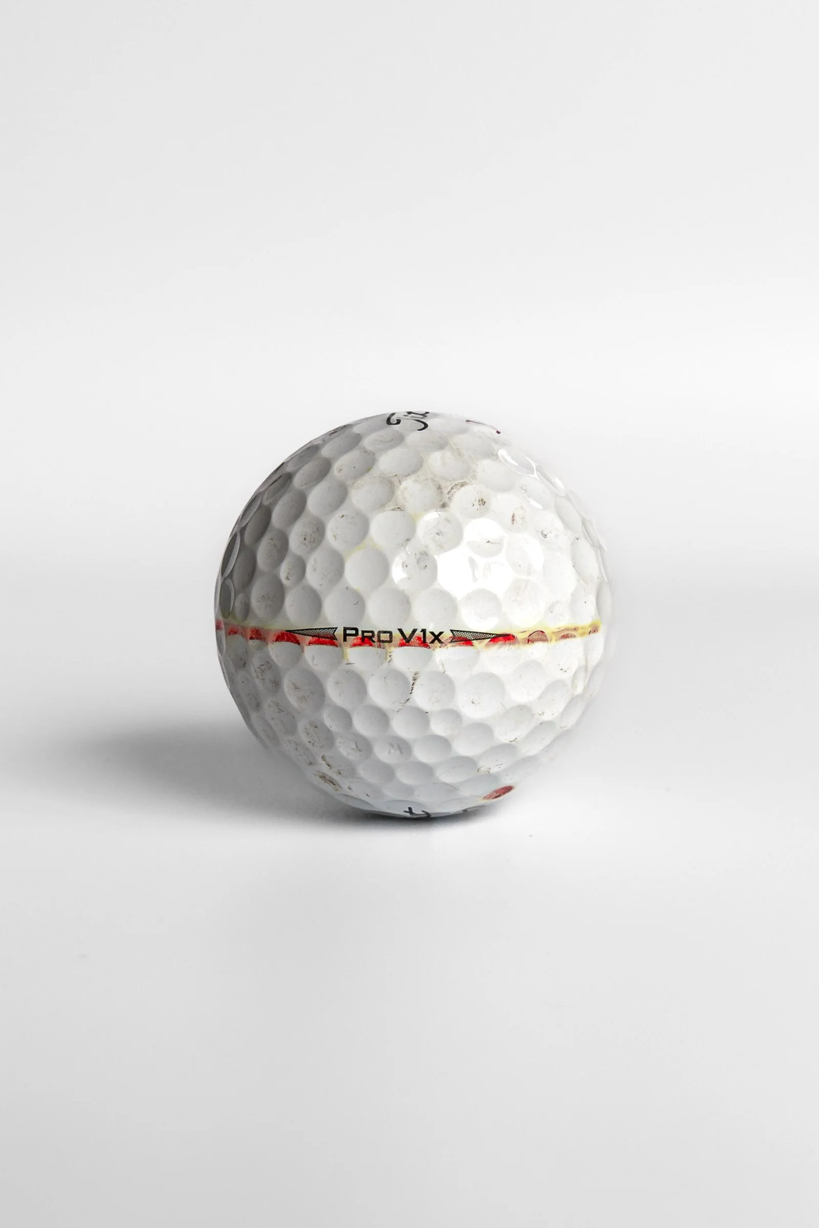 Titleist Pro V1x golf ball with faded red alignment stripe around equator white background