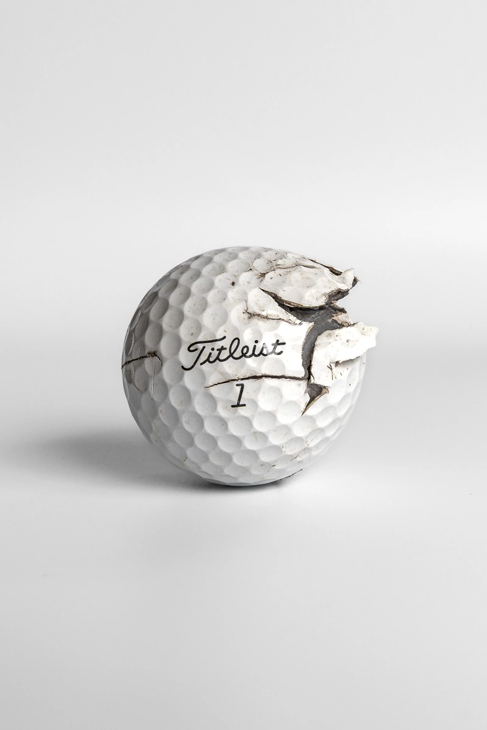 Titleist Pro V1 cracked golf ball with exposed interior layers white background