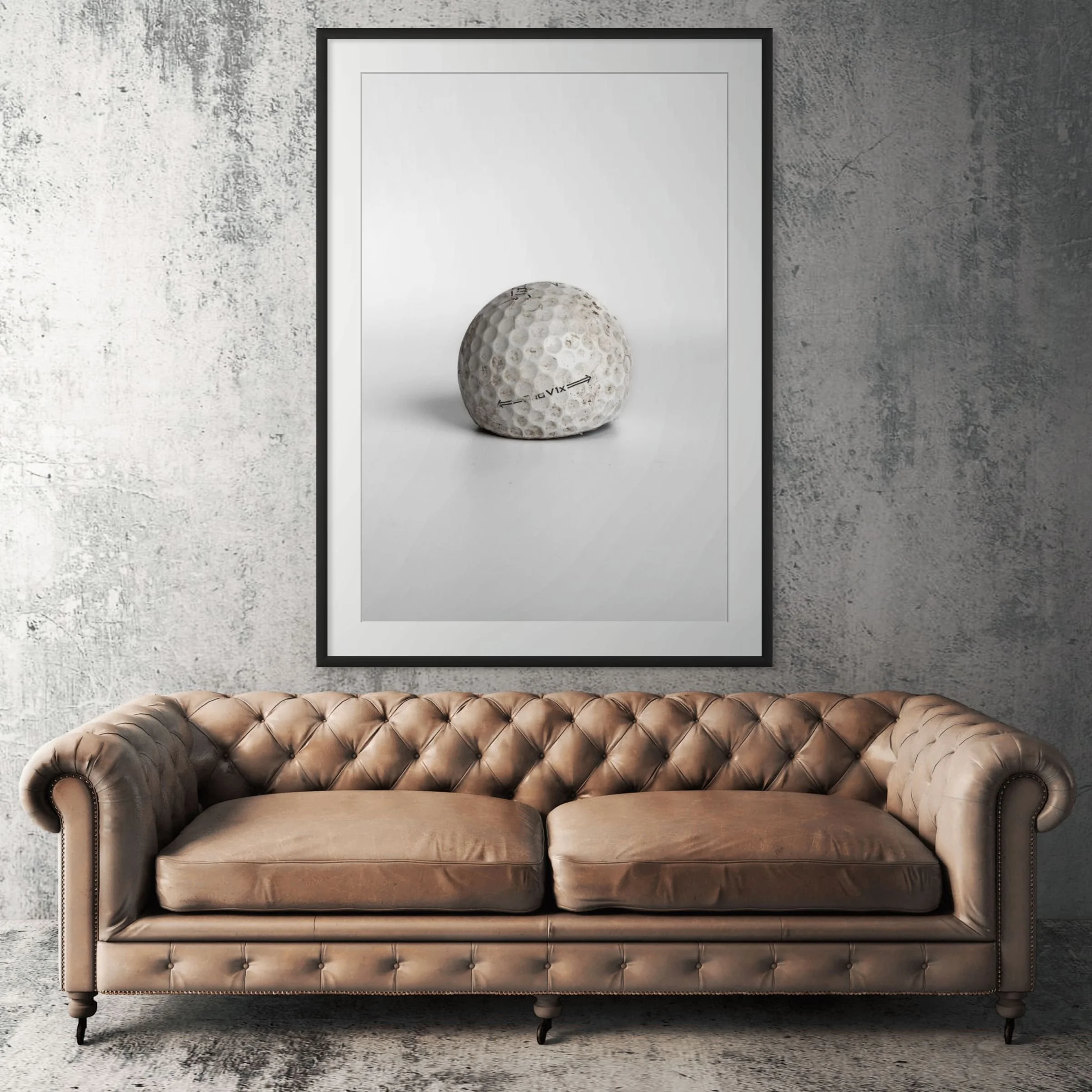Titleist Pro V1x aged golf ball framed print displayed above tan leather sofa in living room
