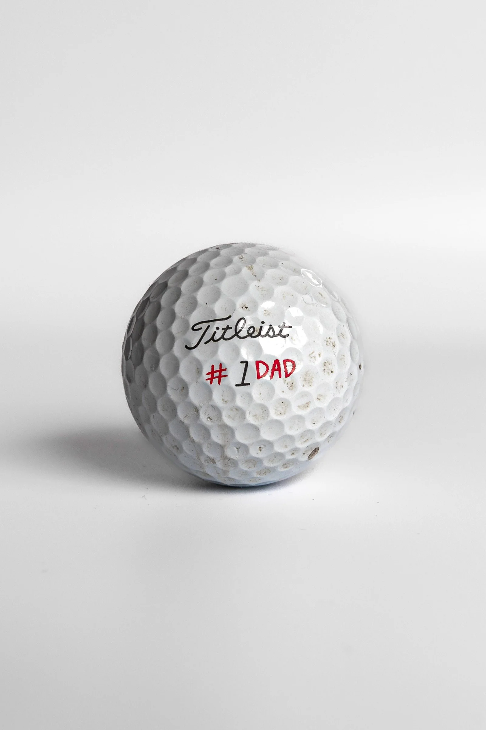 Titleist Pro V1 golf ball with #1 Dad red text white background