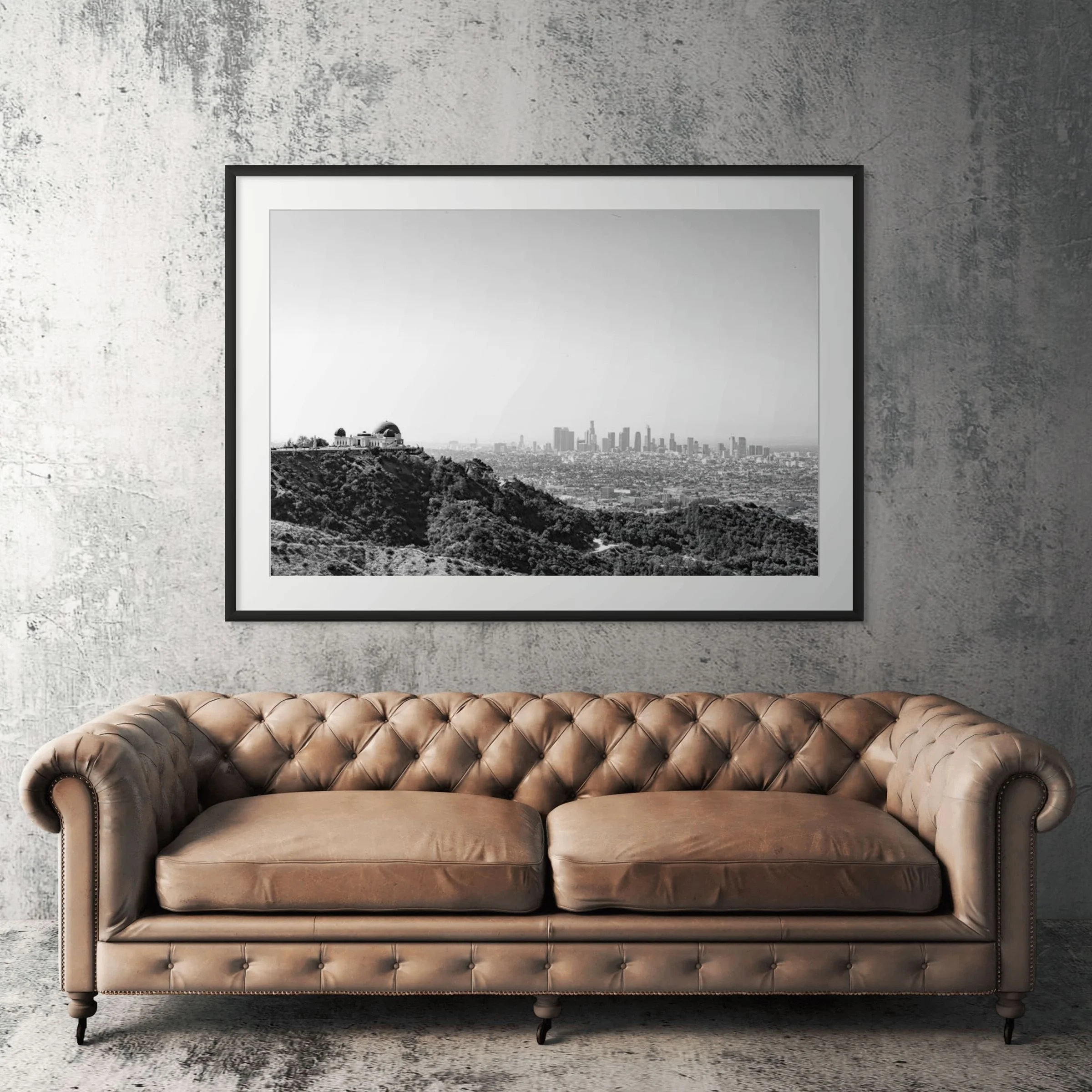 Los Angeles black and white cityscape framed print displayed above tan leather sofa in living room