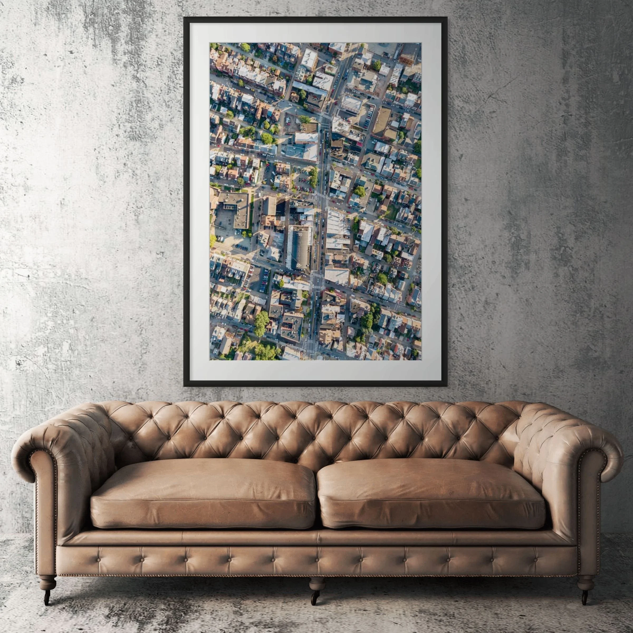 Lawrenceville aerial view framed print displayed above tan leather sofa in living room