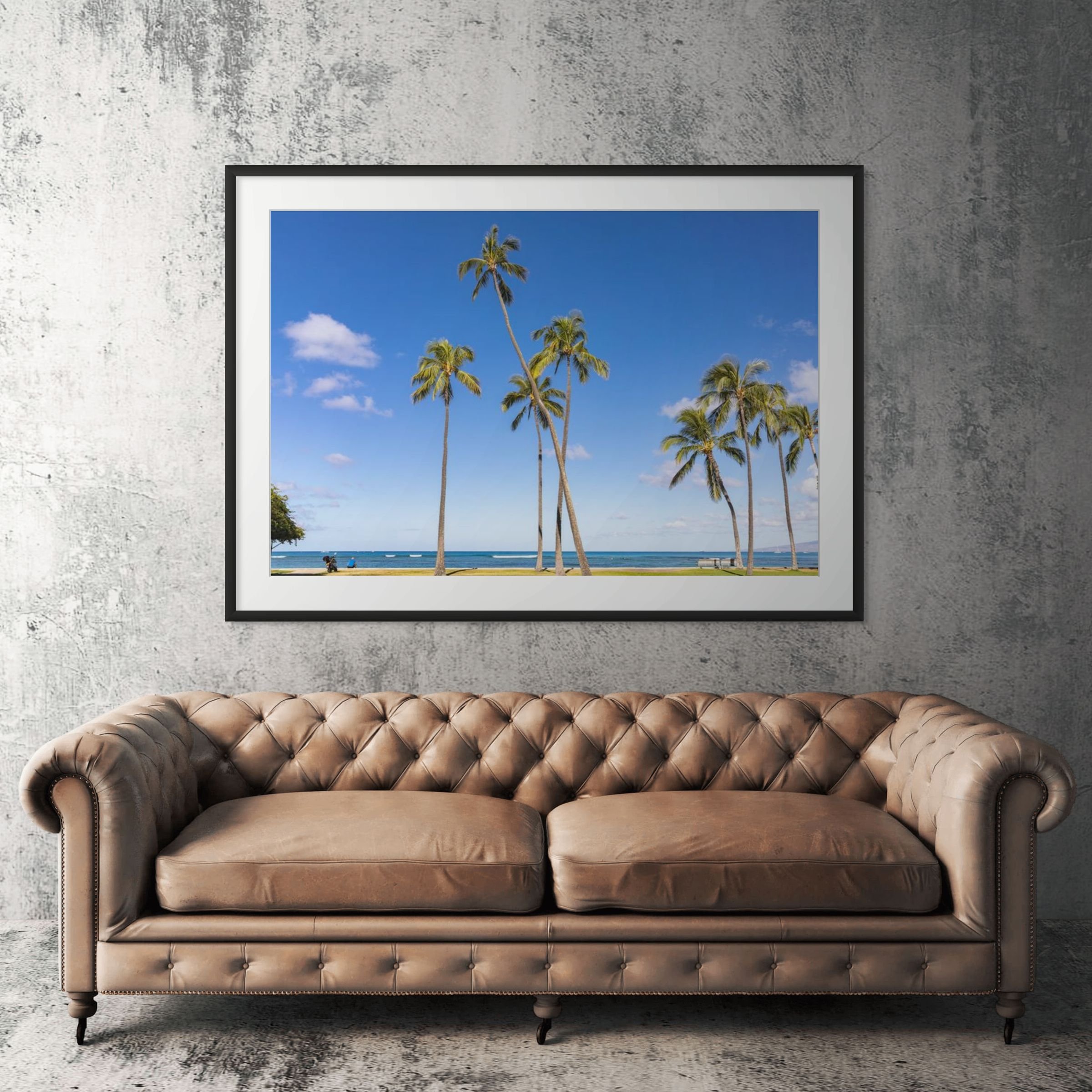 Hawaii ocean view framed print displayed above tan leather sofa in living room
