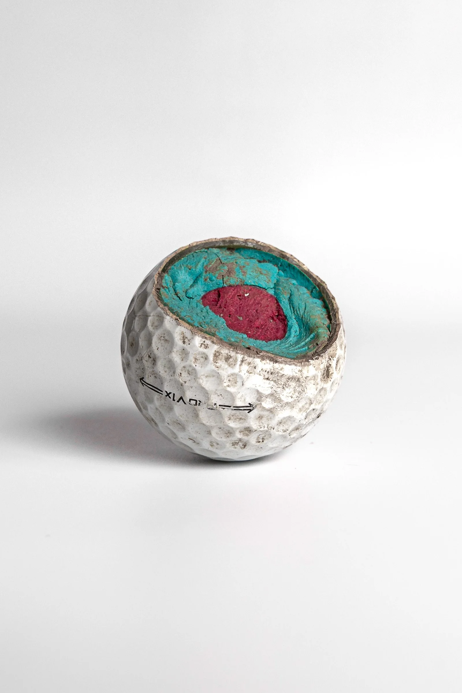 Titleist Pro V1 cut open showing turquoise and pink interior core layers white background