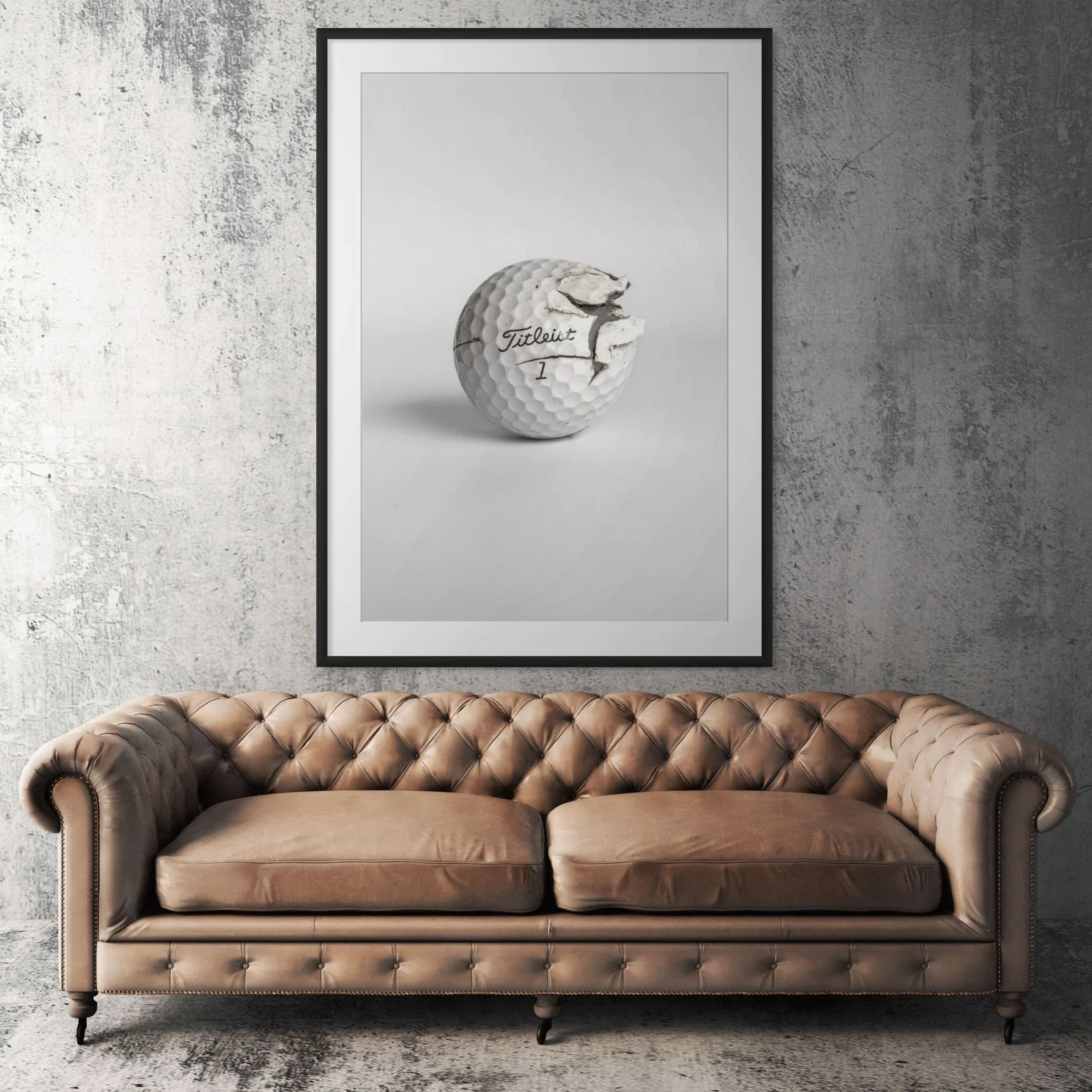 Titleist Pro V1 cracked golf ball framed print displayed above tan leather sofa in living room