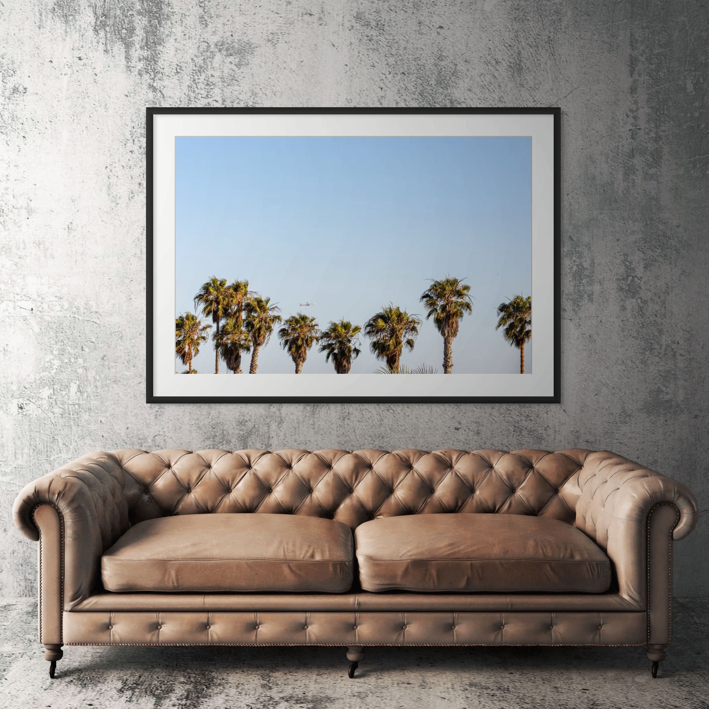 Los Angeles palm trees framed print displayed above tan leather sofa in living room