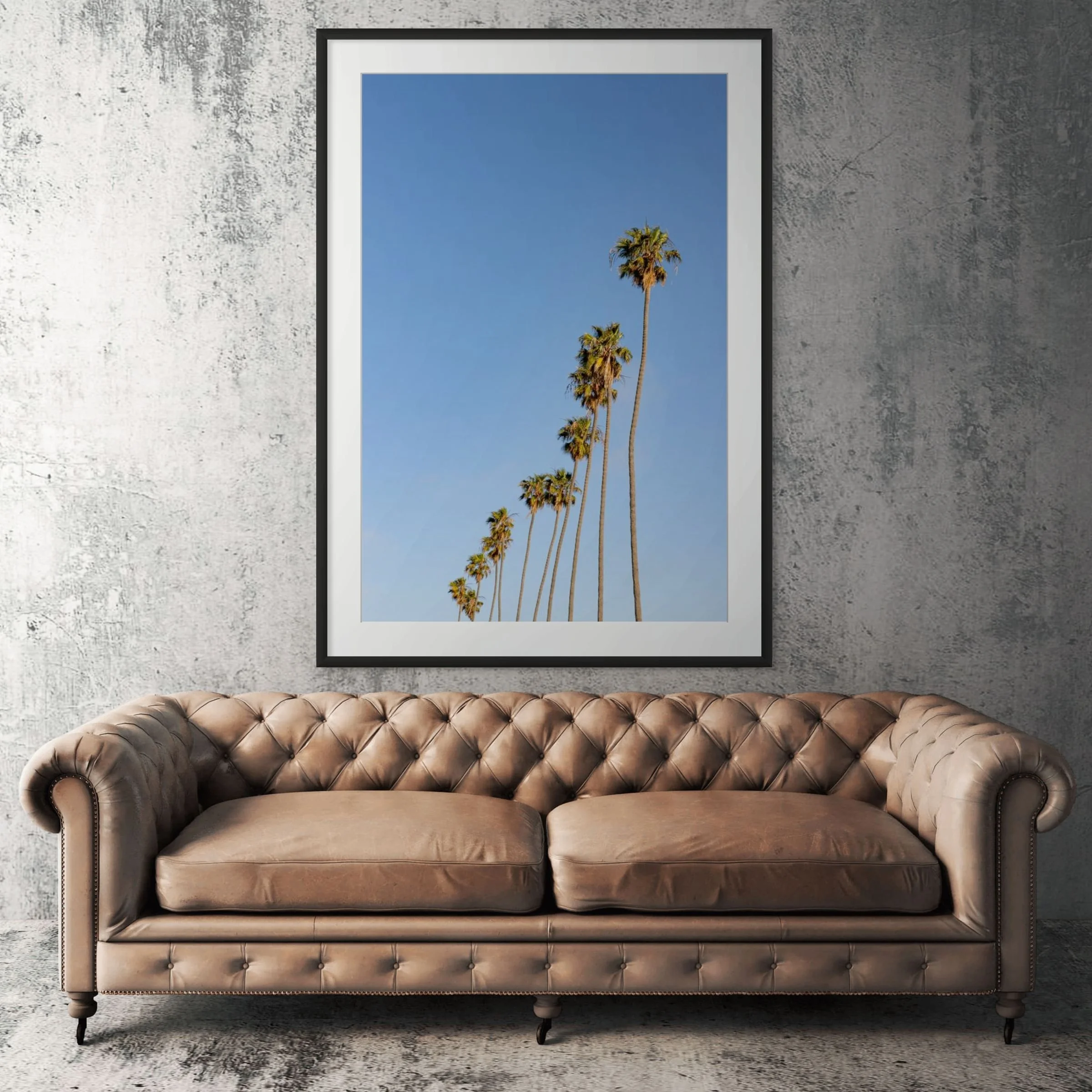 Hollywood palm trees framed print displayed above tan leather sofa in living room