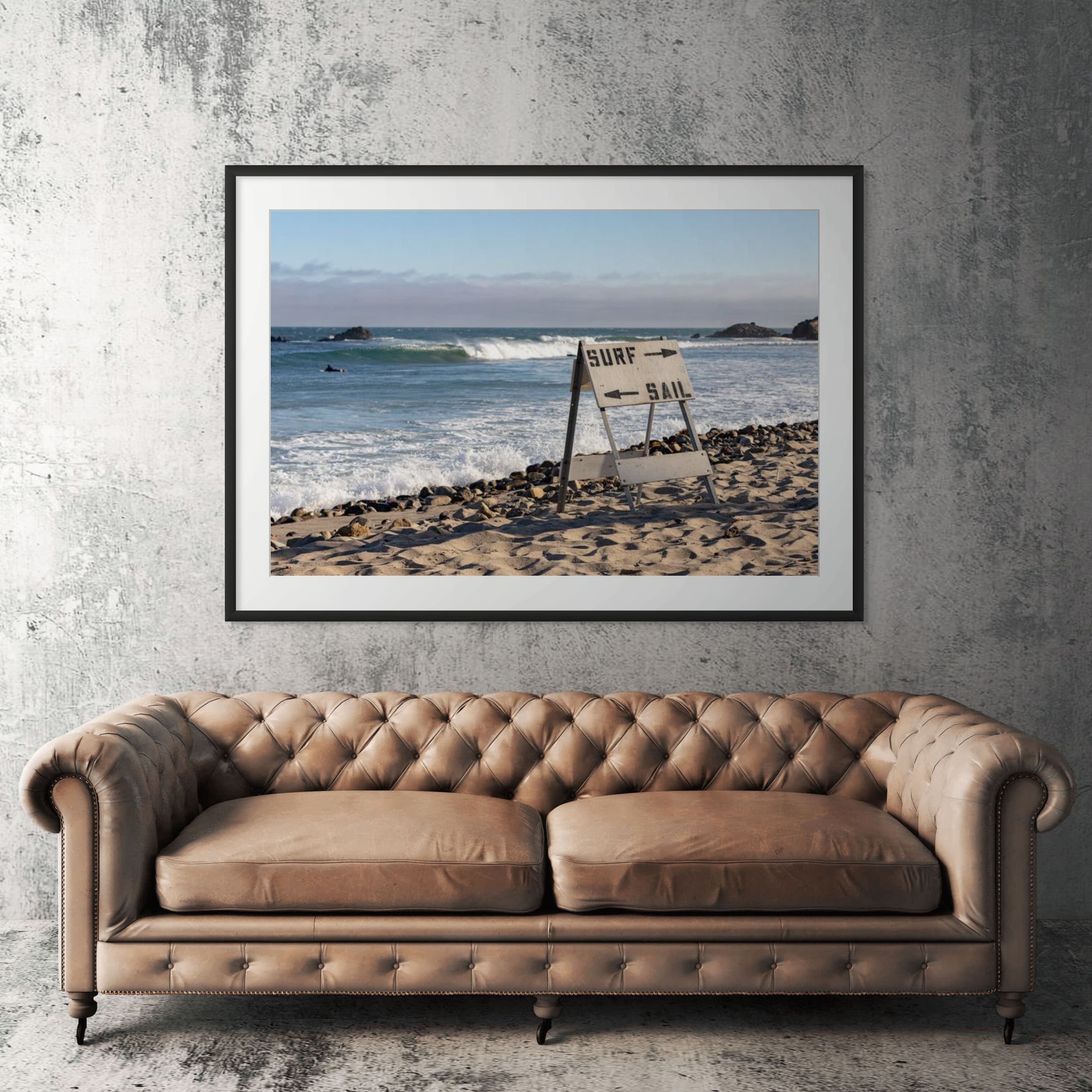 Malibu surf sail sign framed print displayed above tan leather sofa in living room